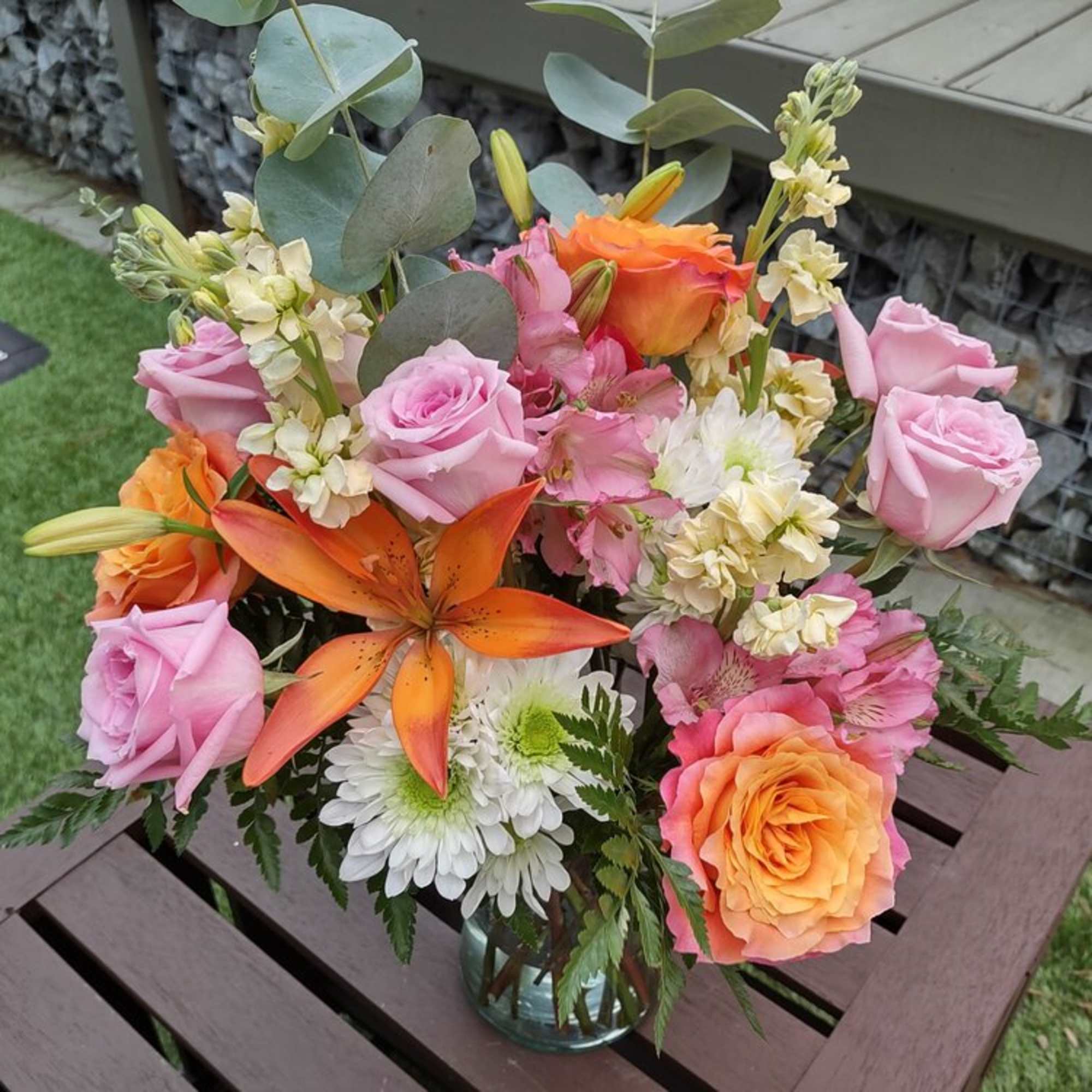 Bouquet of pink and orange roses with lilies in a glass vase