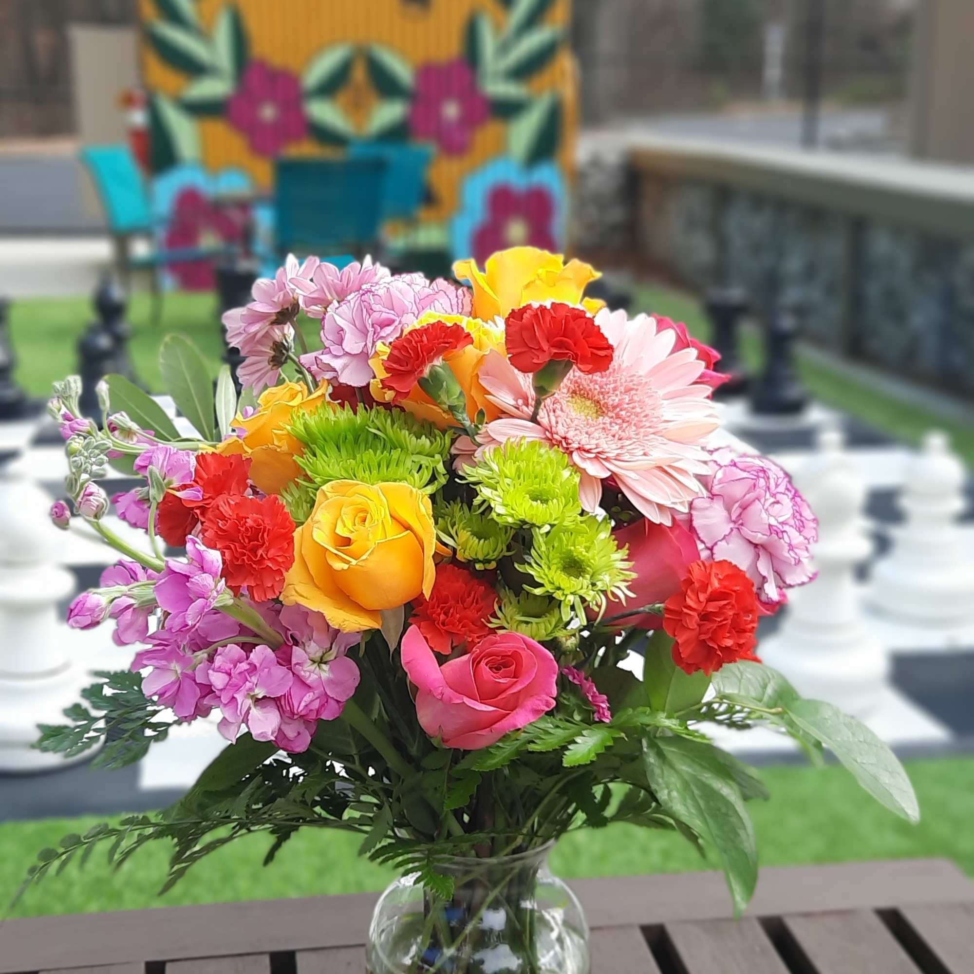 Mixed bouquet of roses, gerbera daisies, carnations, and green mums in a glass vase