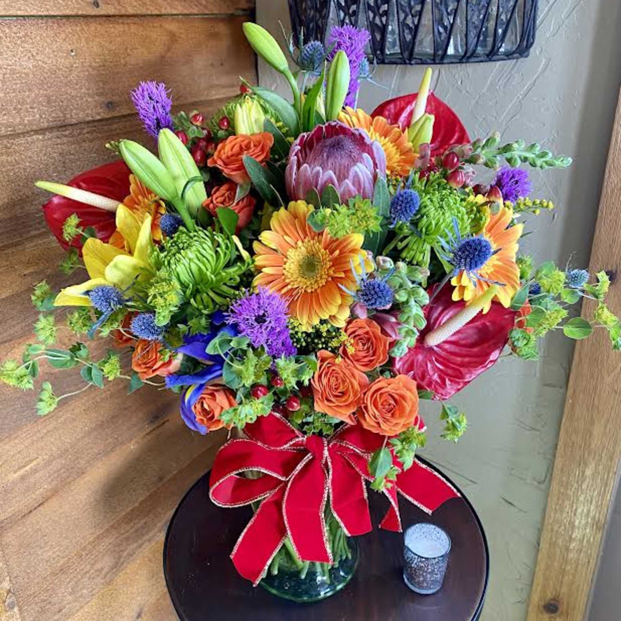 Colorful mixed bouquet in a glass vase with a red ribbon