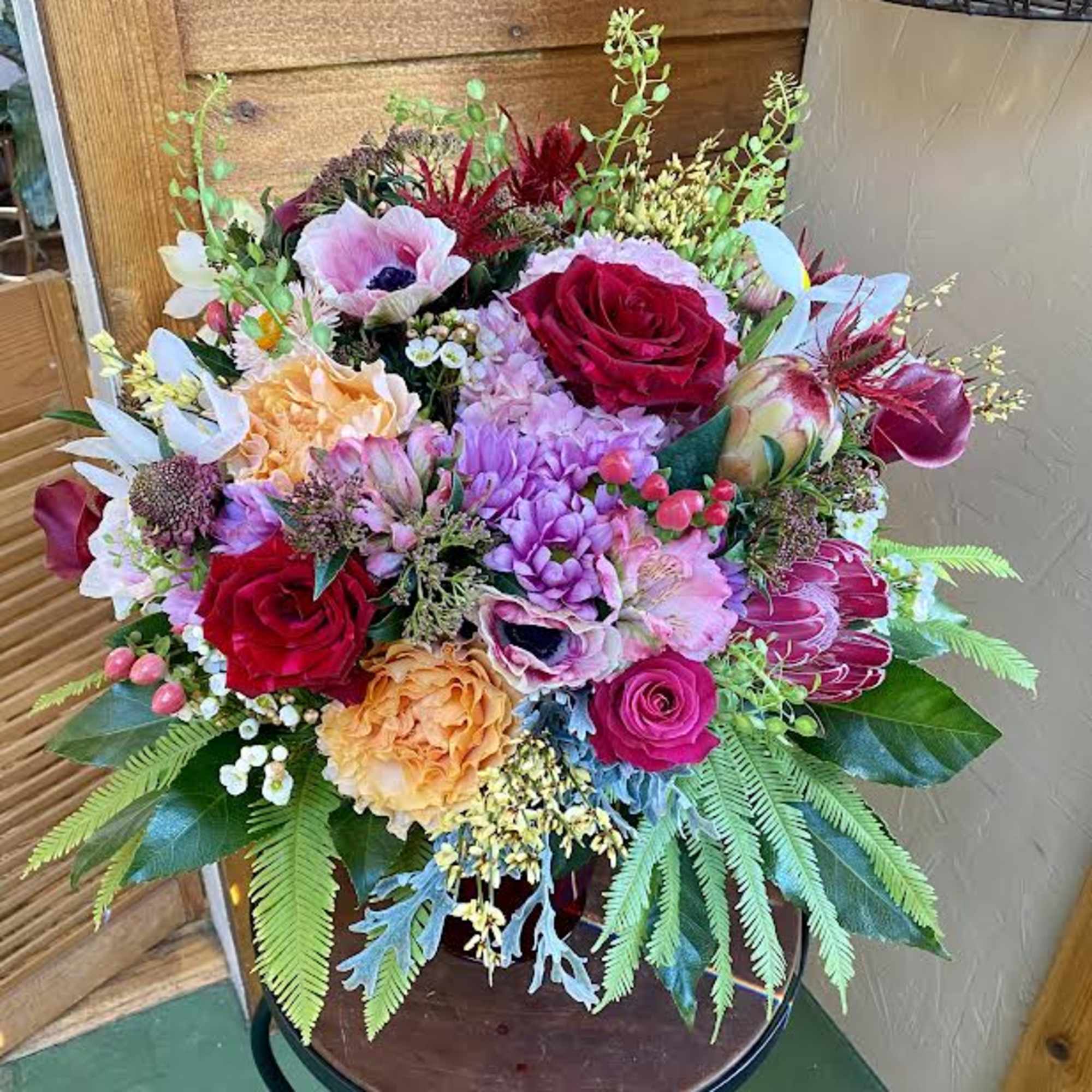 Colorful mixed bouquet in a vase with roses, hydrangea, and protea