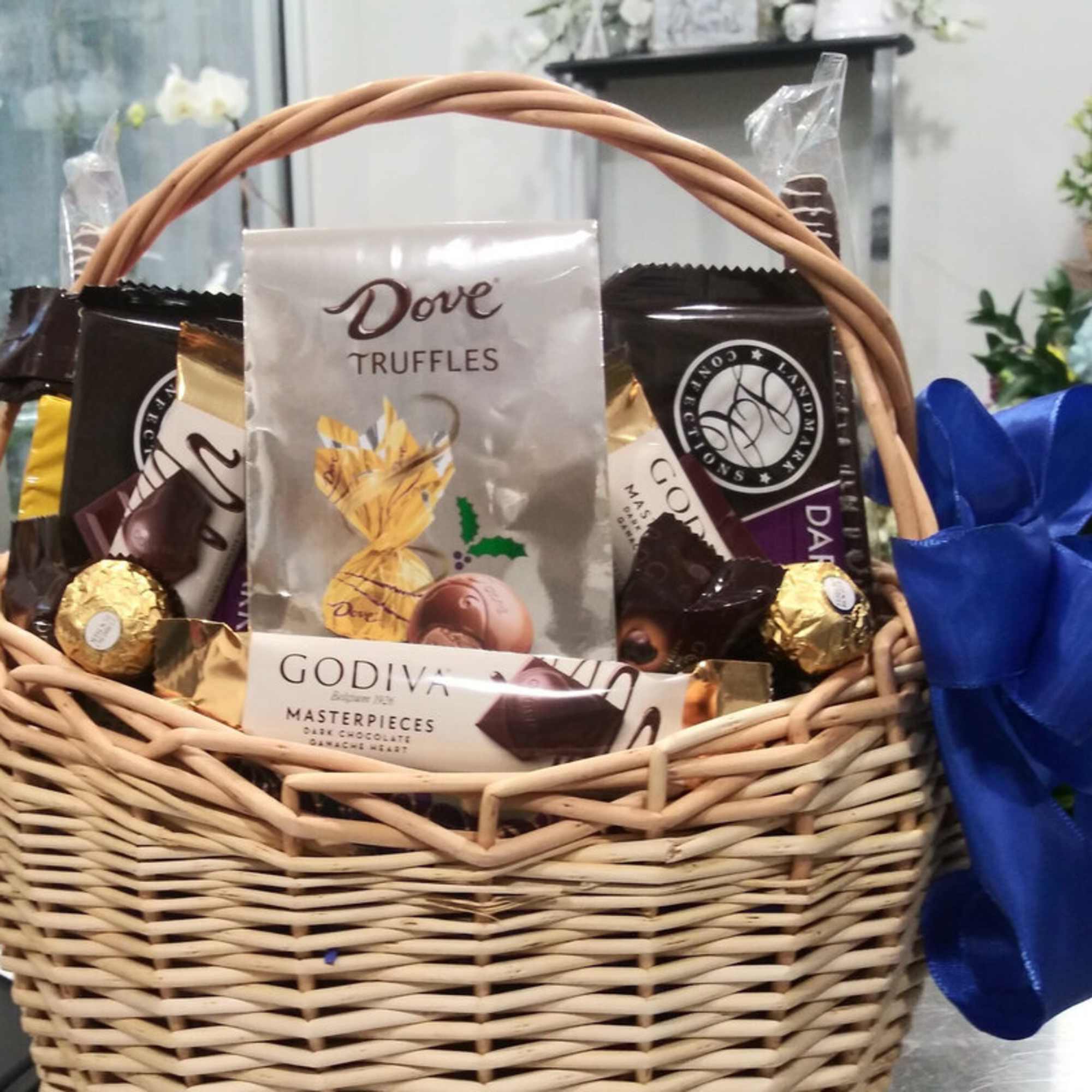 Wicker basket filled with assorted chocolates and a blue ribbon bow
