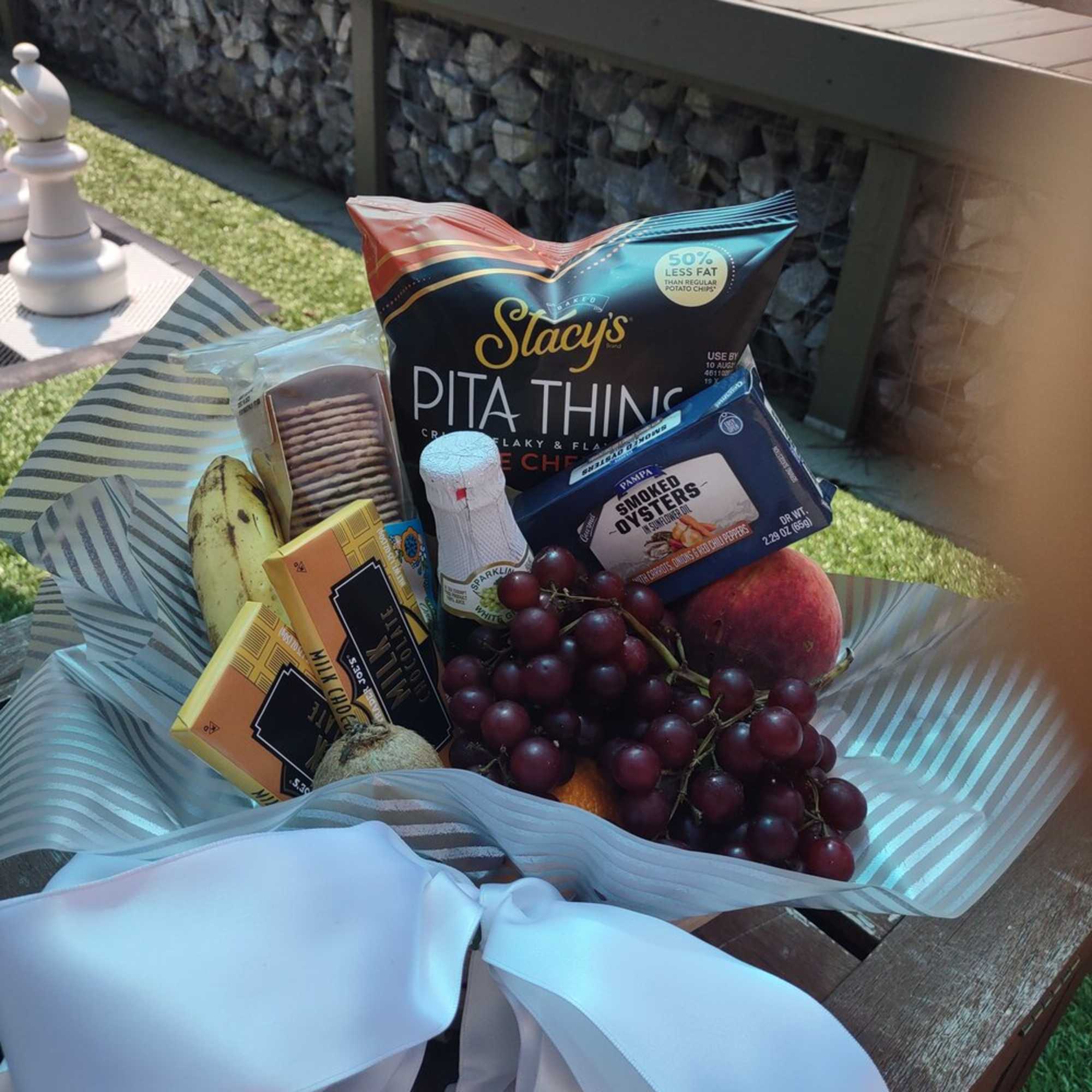 Gift basket with snacks, fruit, and a white ribbon