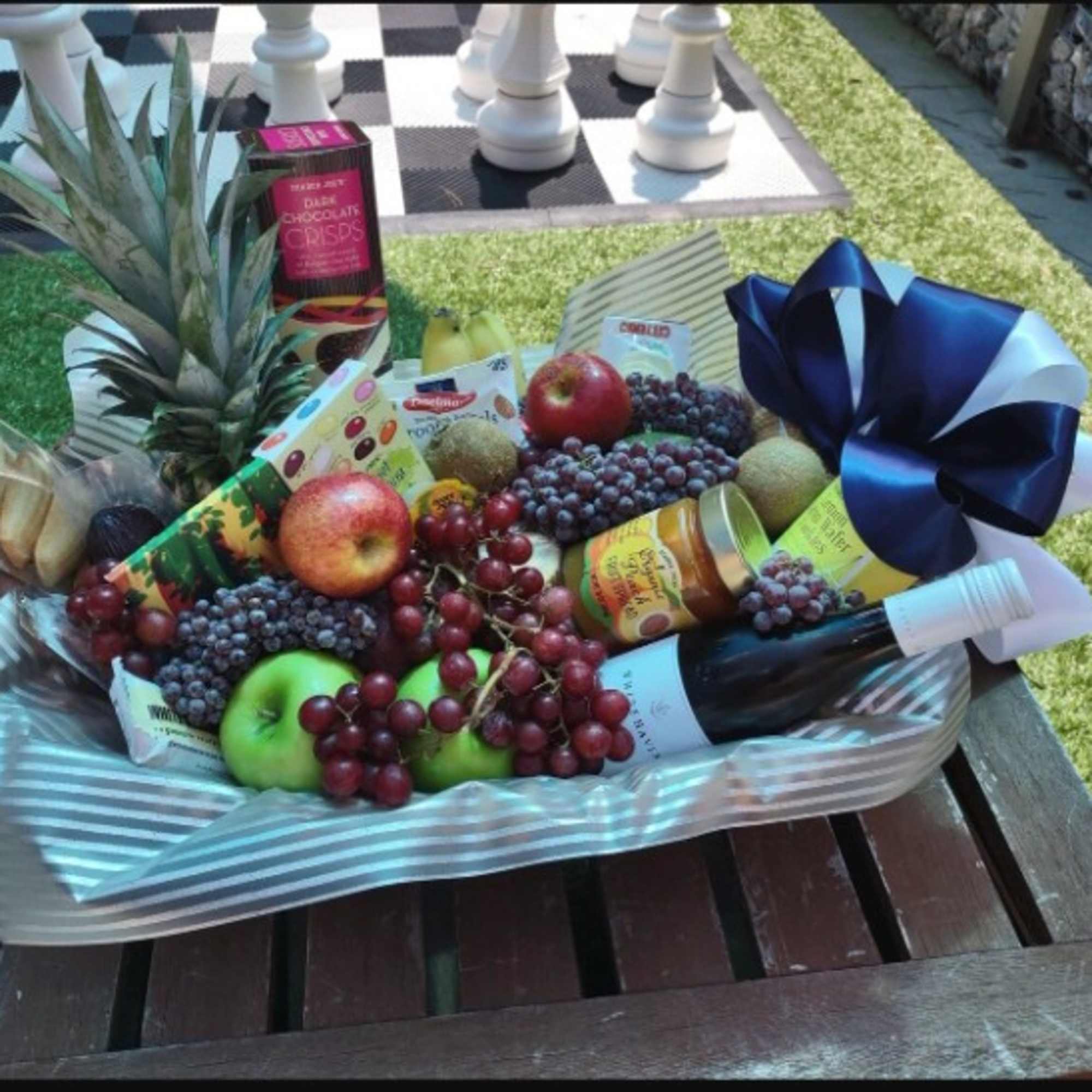Fruit gift basket with apples, grapes, pineapple, and packaged snacks