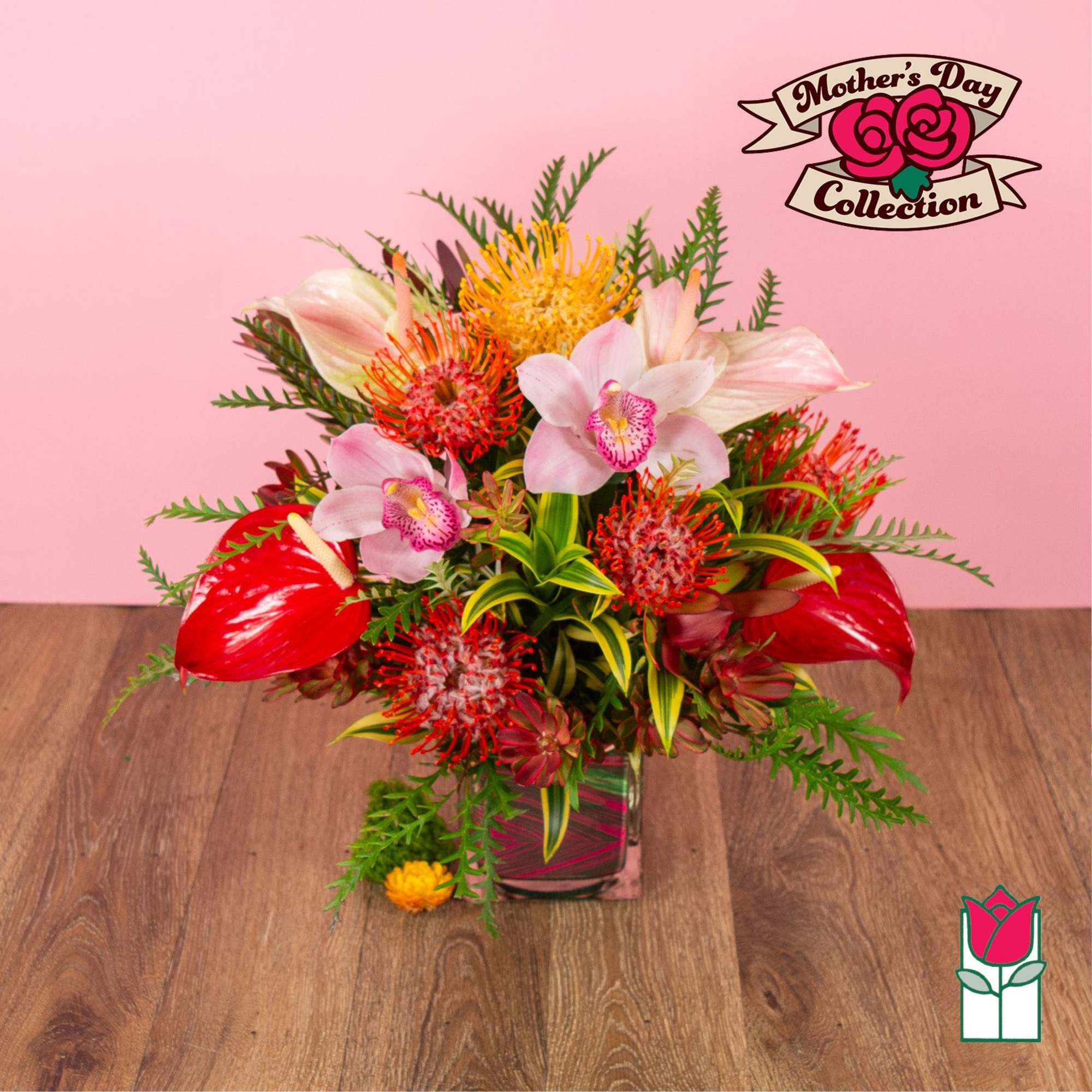 Bright tropical arrangement with pink orchids, red anthurium, and orange blooms in a glass cube vase
