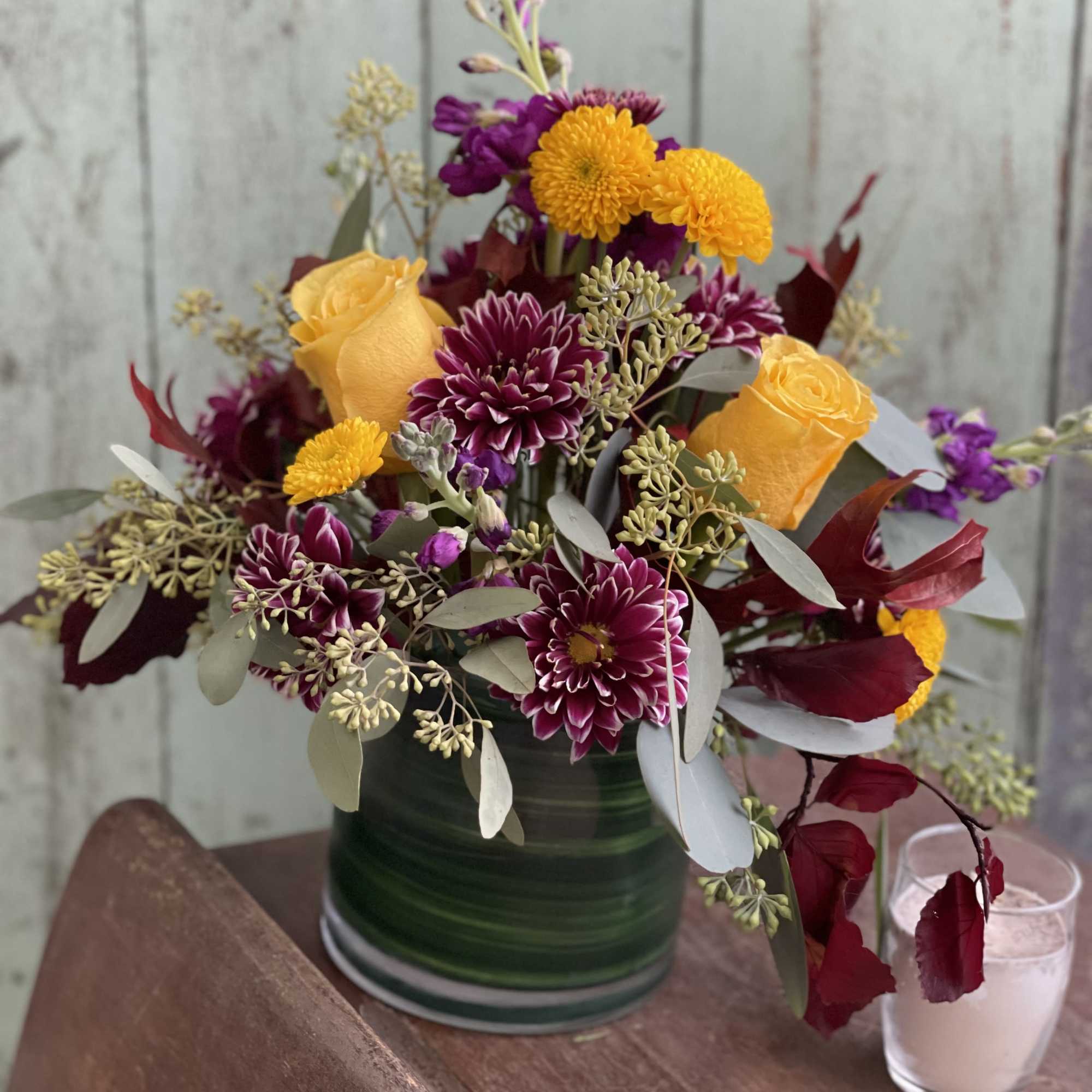 Bouquet of yellow roses and purple chrysanthemums in a green vase