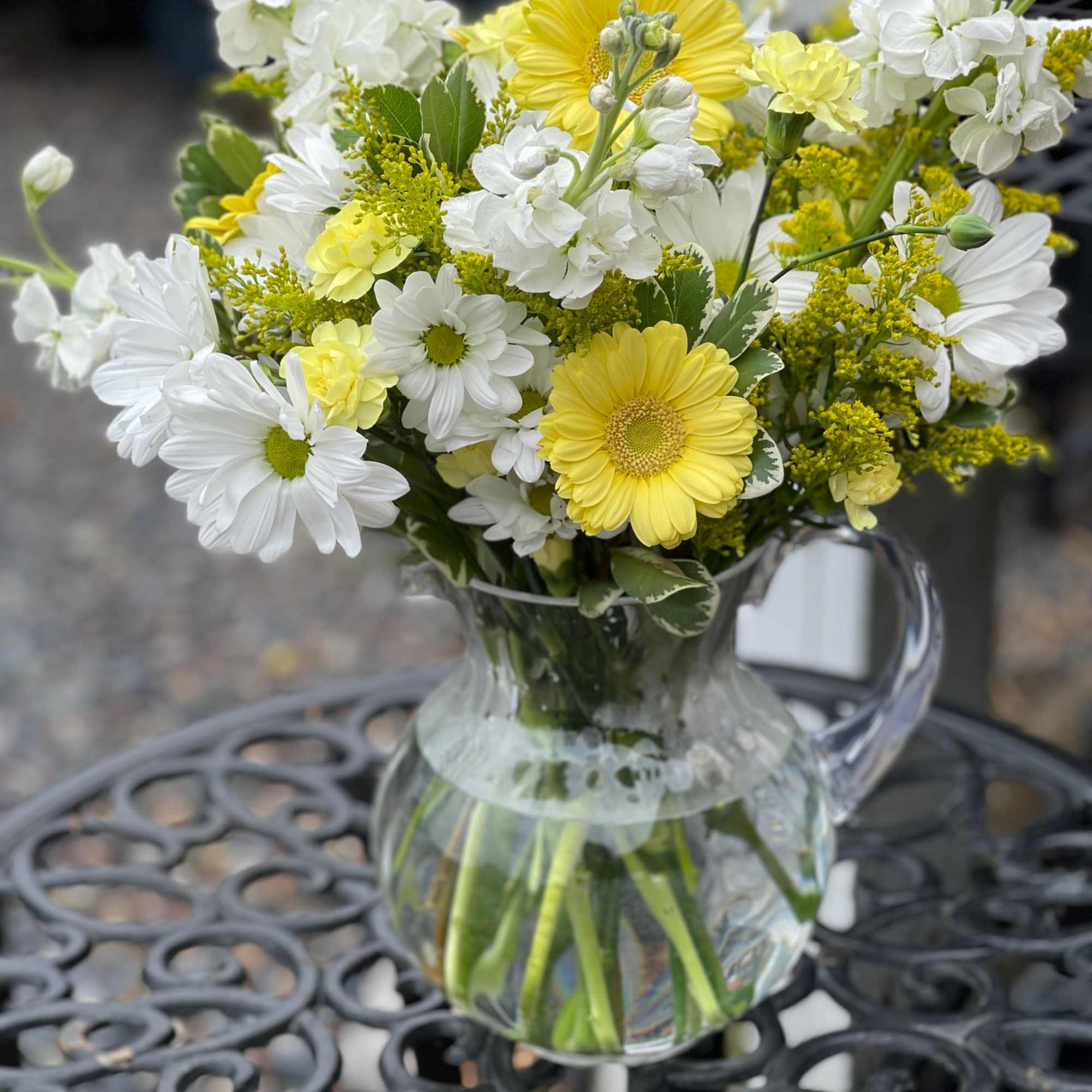 Yellow and white mixed bouquet in a clear glass pitcher vase