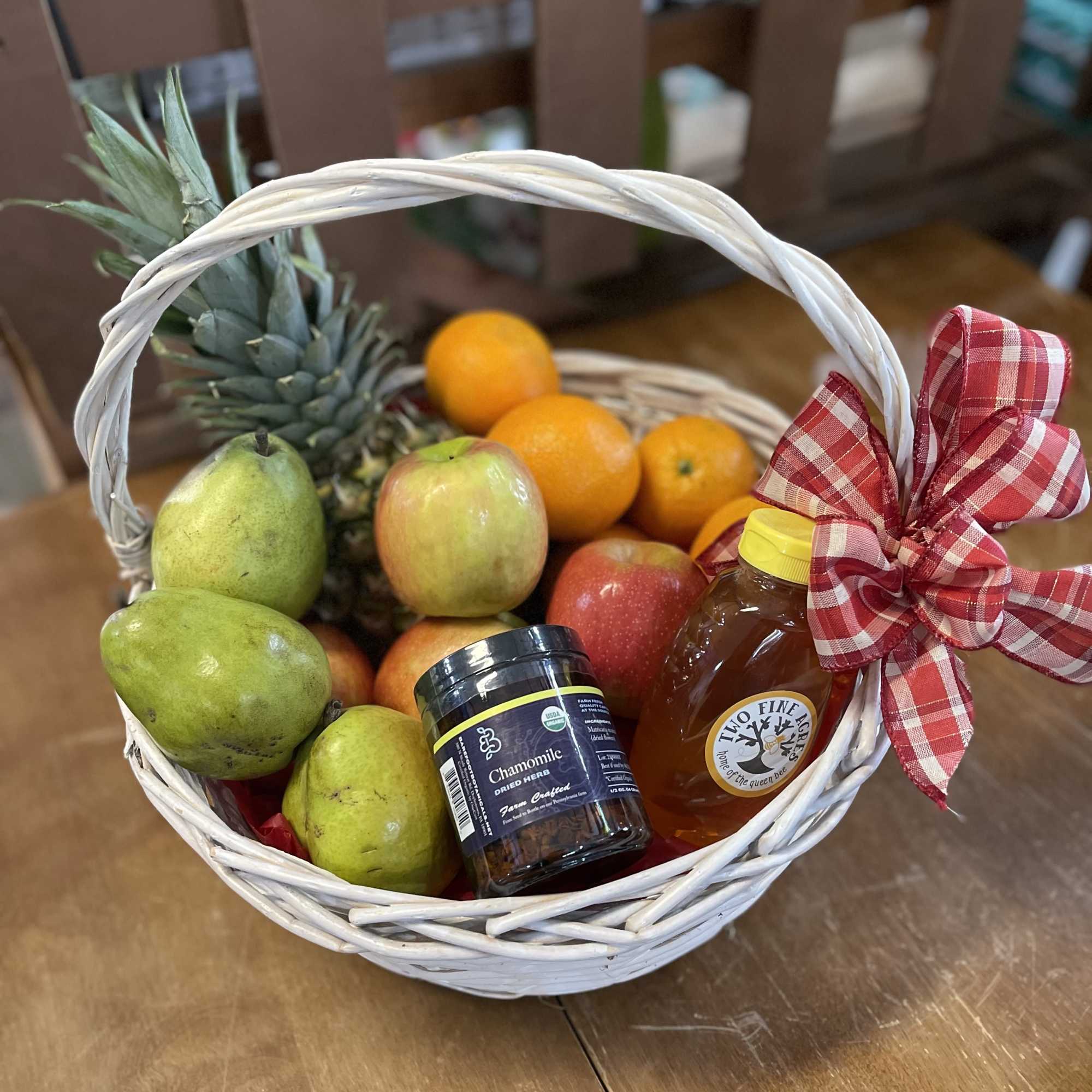 Fruit basket with pineapple, pears, oranges, honey, and dried herbs