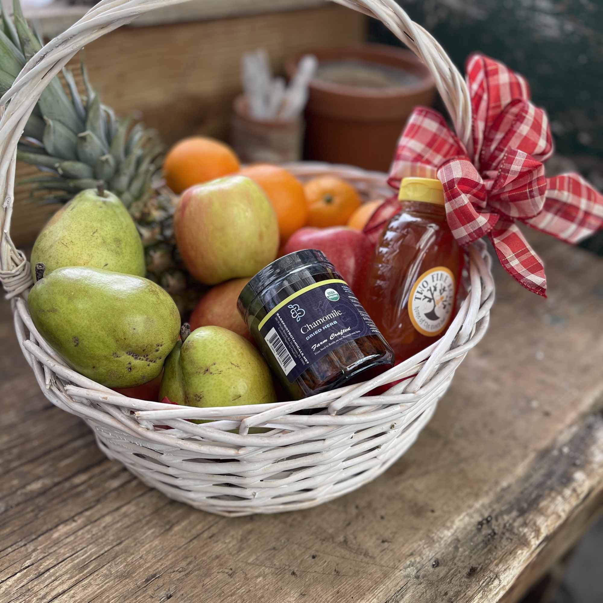 Fruit basket with pears, oranges, honey, and dried chamomile in a white wicker basket
