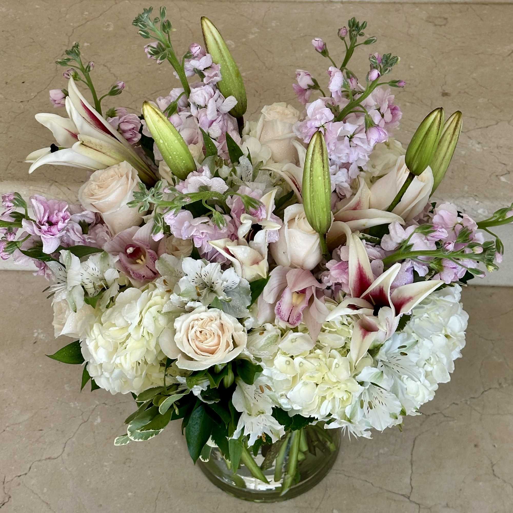 Bouquet of white lilies, roses, and pale pink flowers in a glass vase