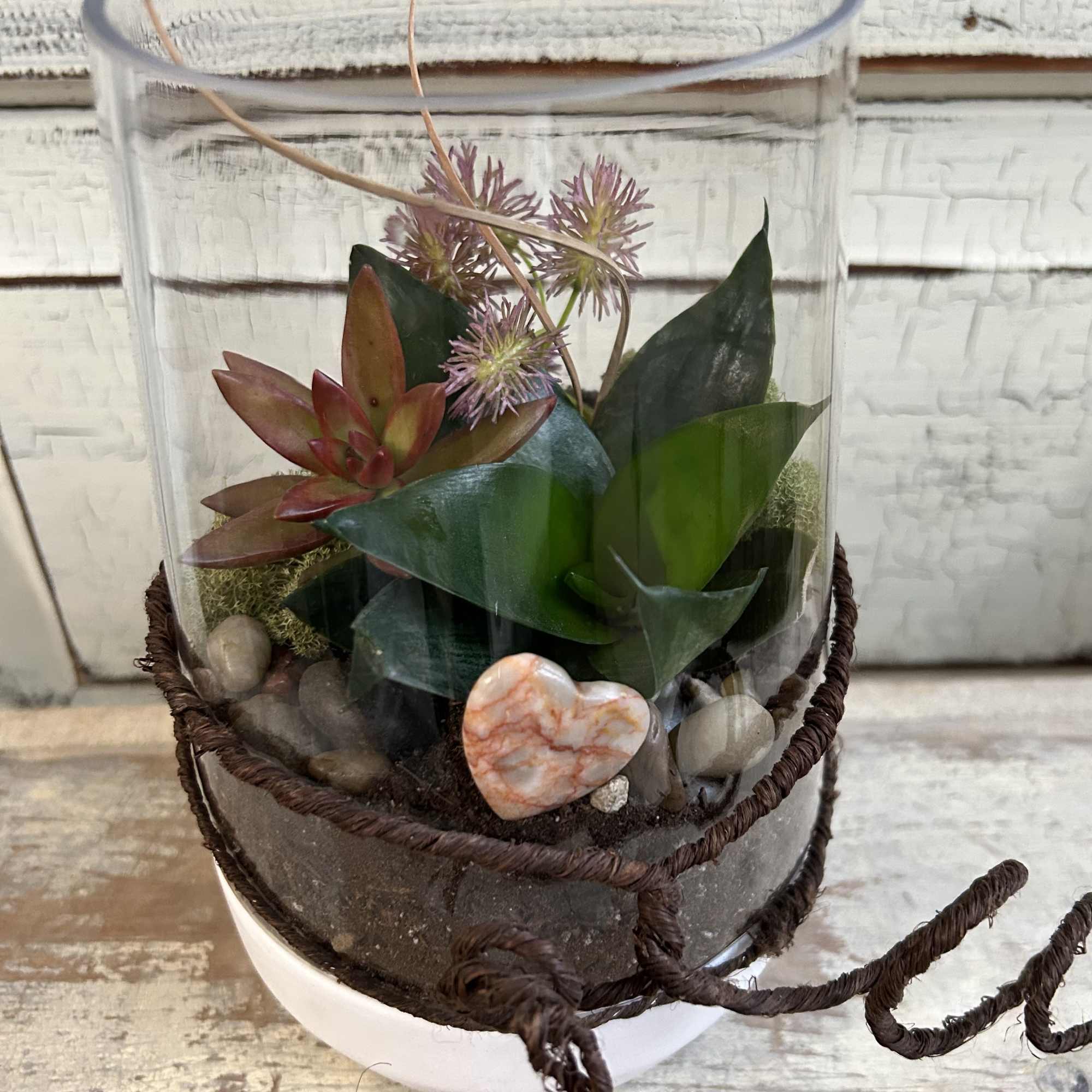Succulent arrangement in a glass cylinder with stones and a heart accent