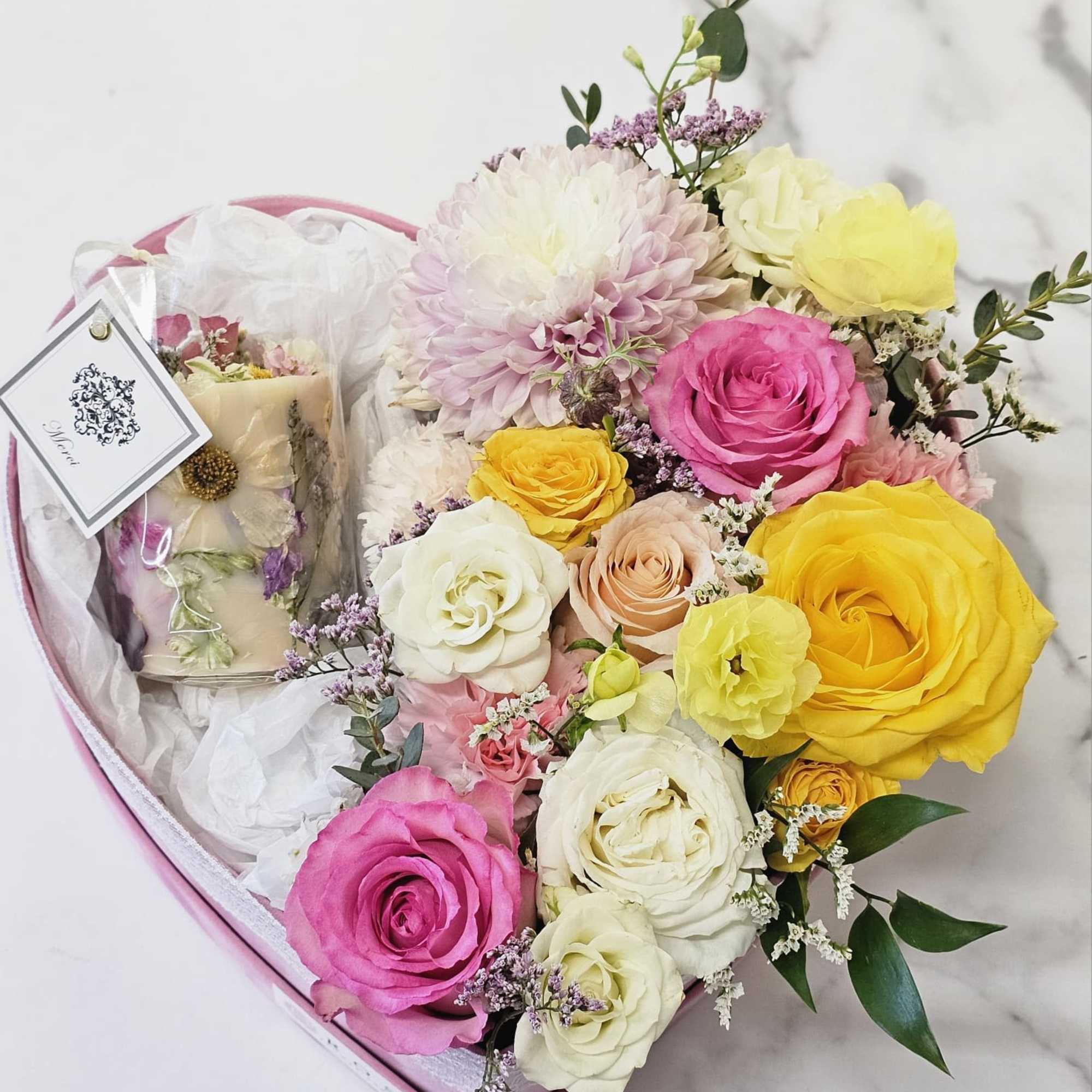 A romantic heart-shaped box filled with pastel roses and seasonal blooms, paired