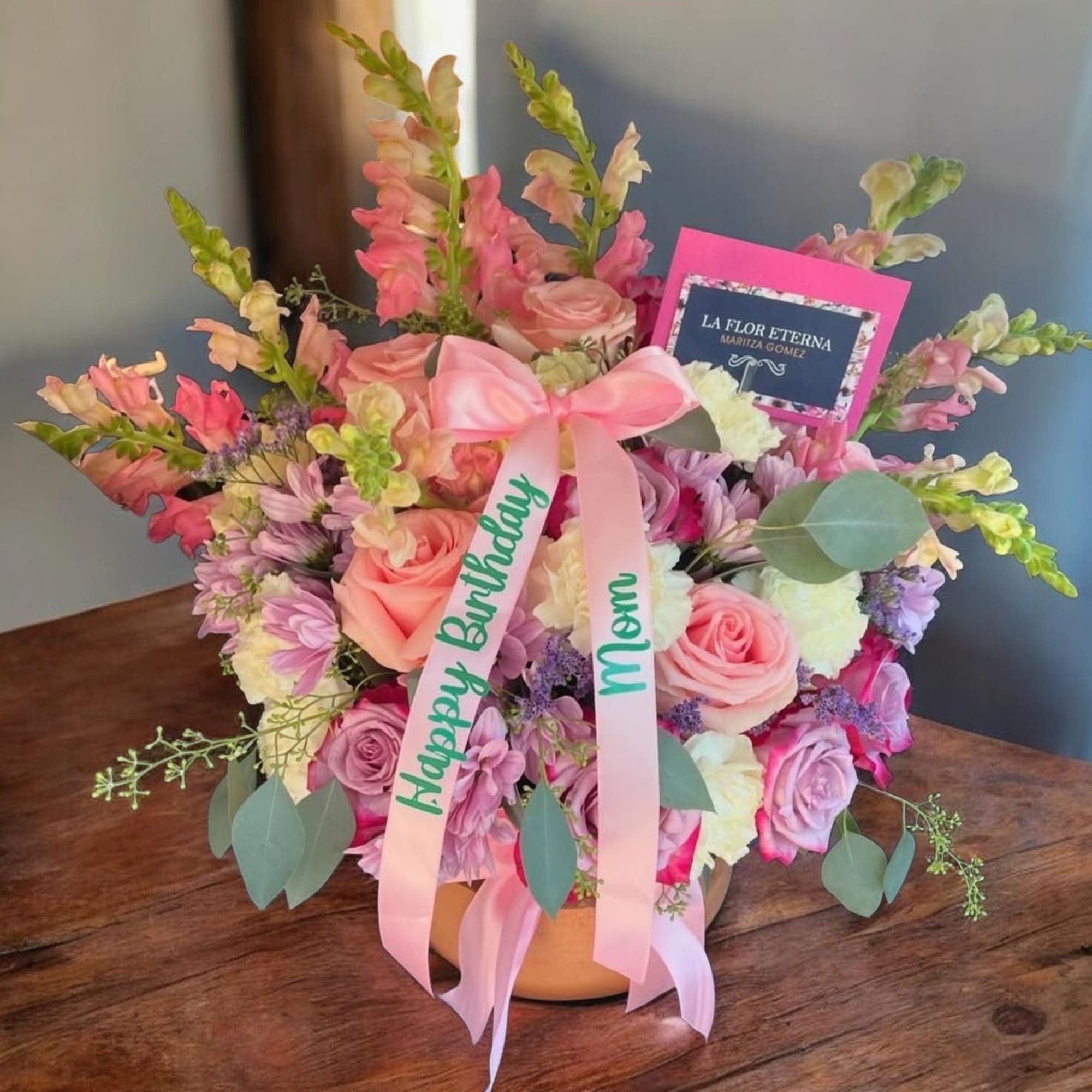 A soft, rounded bouquet of pink and peach roses accented with tall
