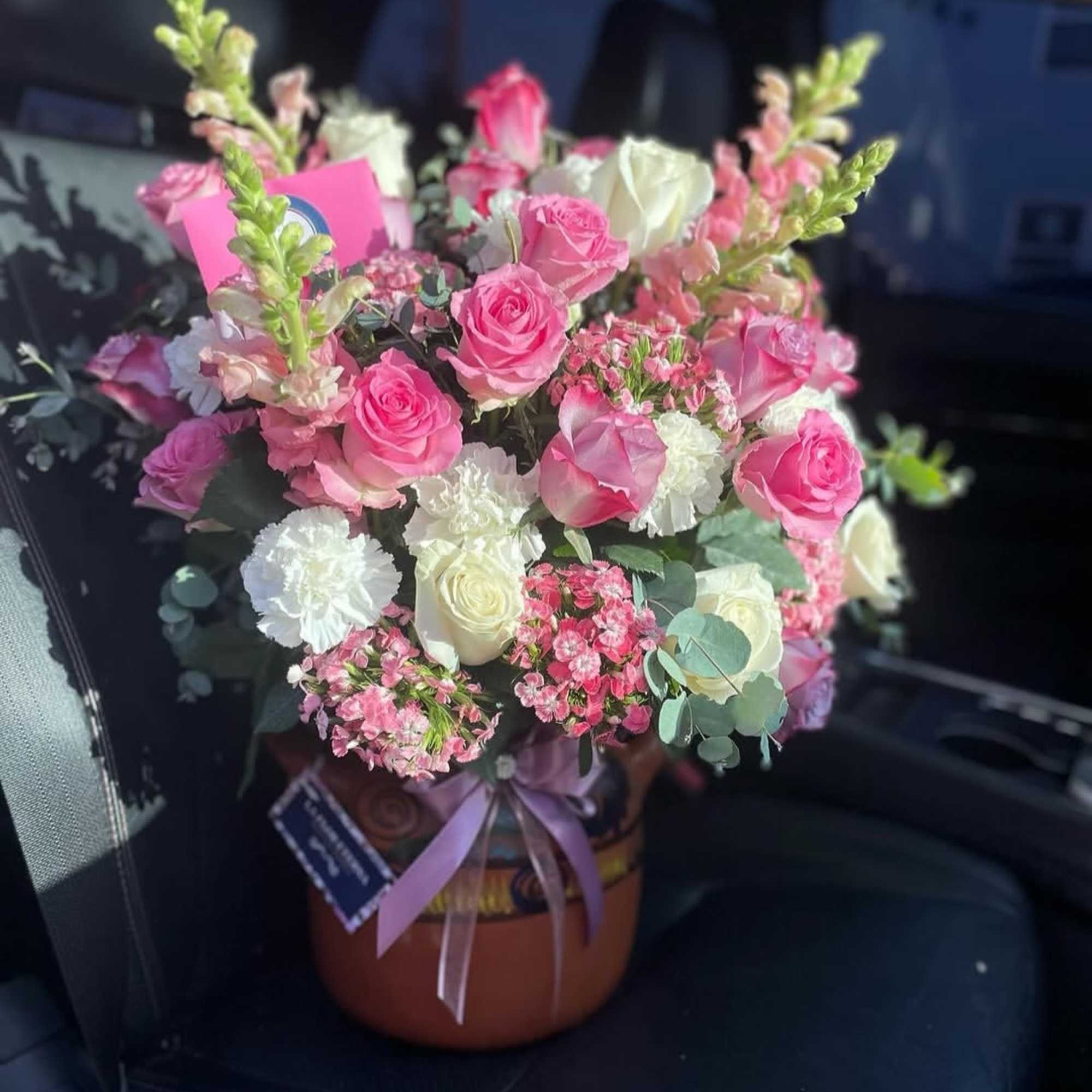 A soft, rounded bouquet of pink and peach roses accented with tall