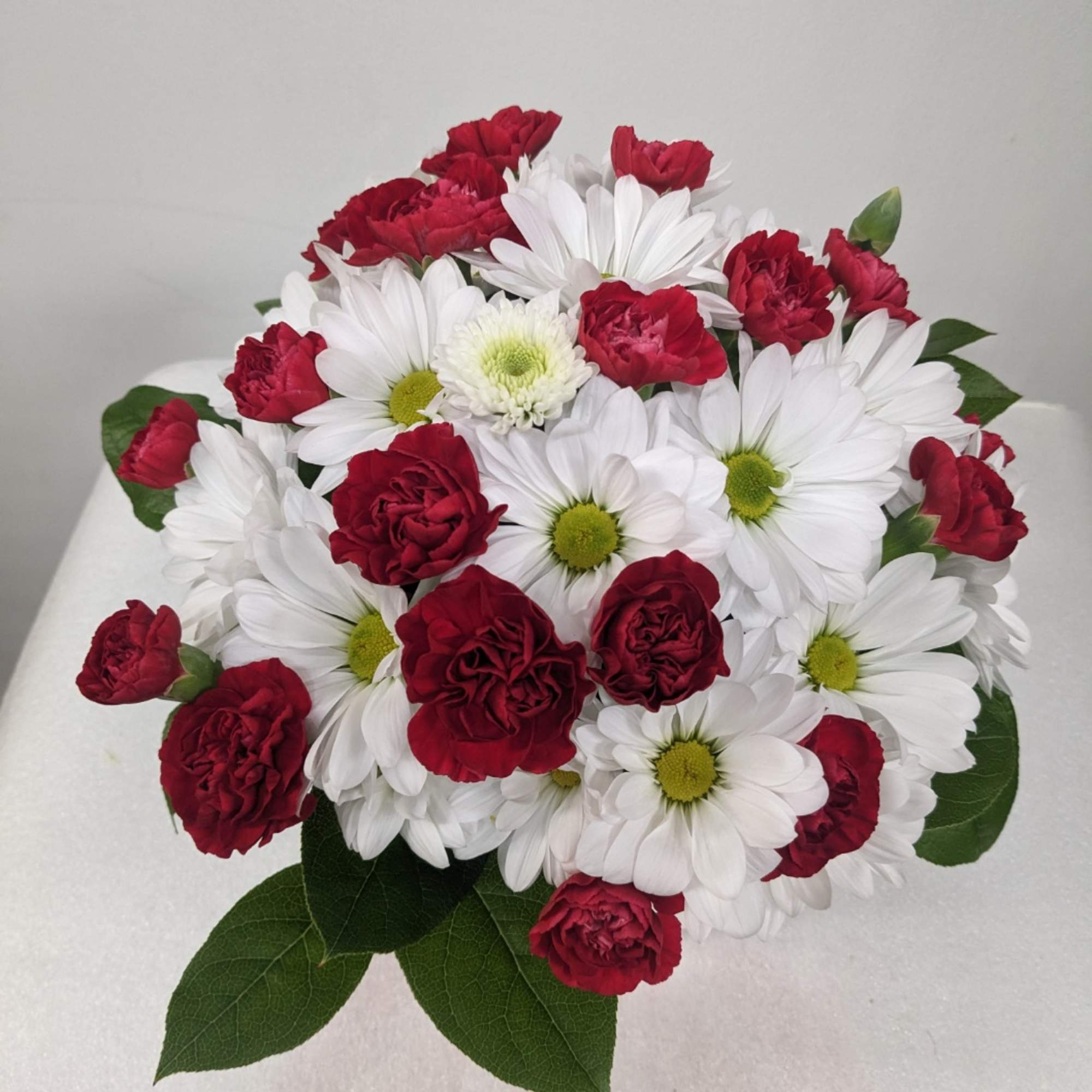 Bouquet of red carnations and white daisies with green centers