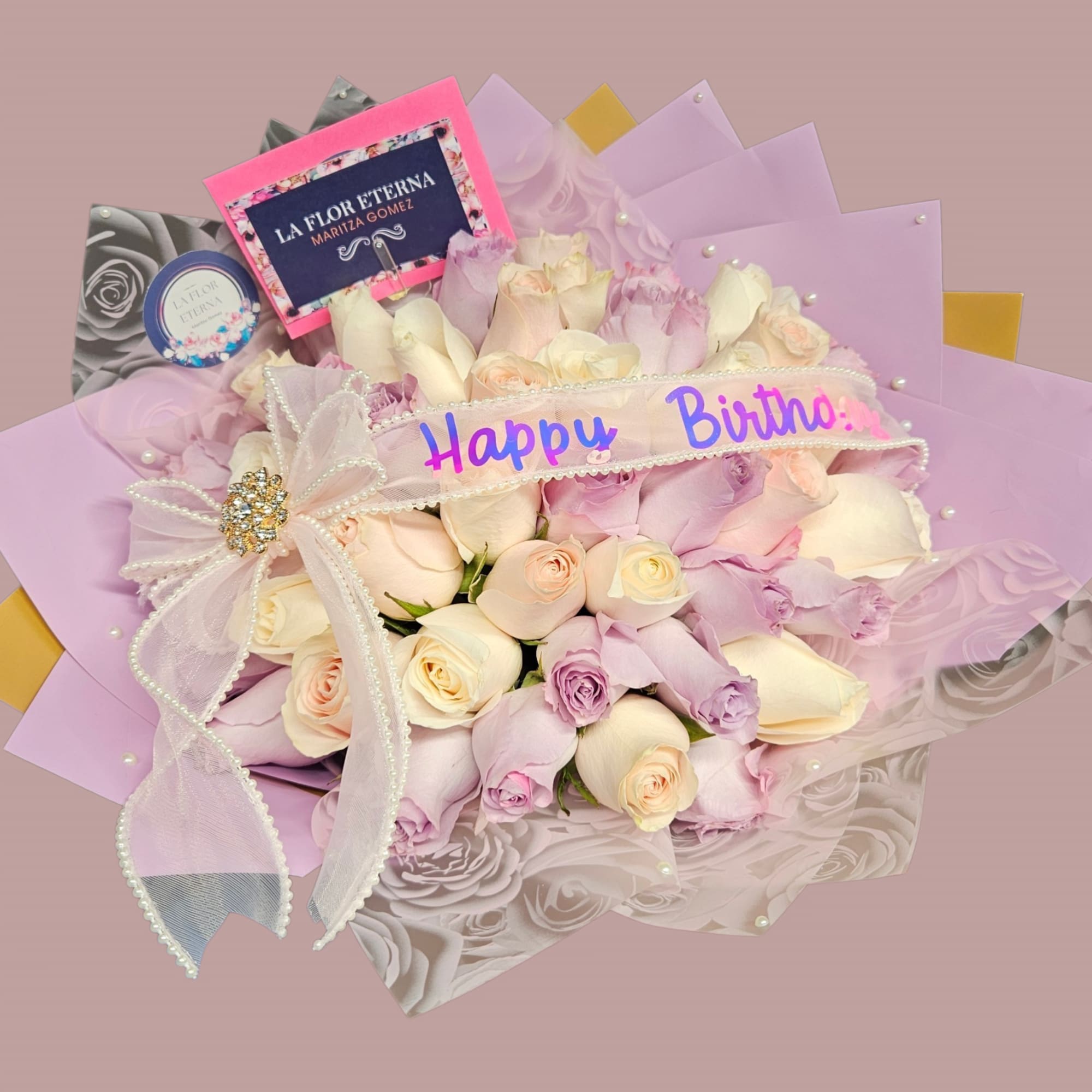 A rounded birthday bouquet of roses in soft blush, cream and lavender