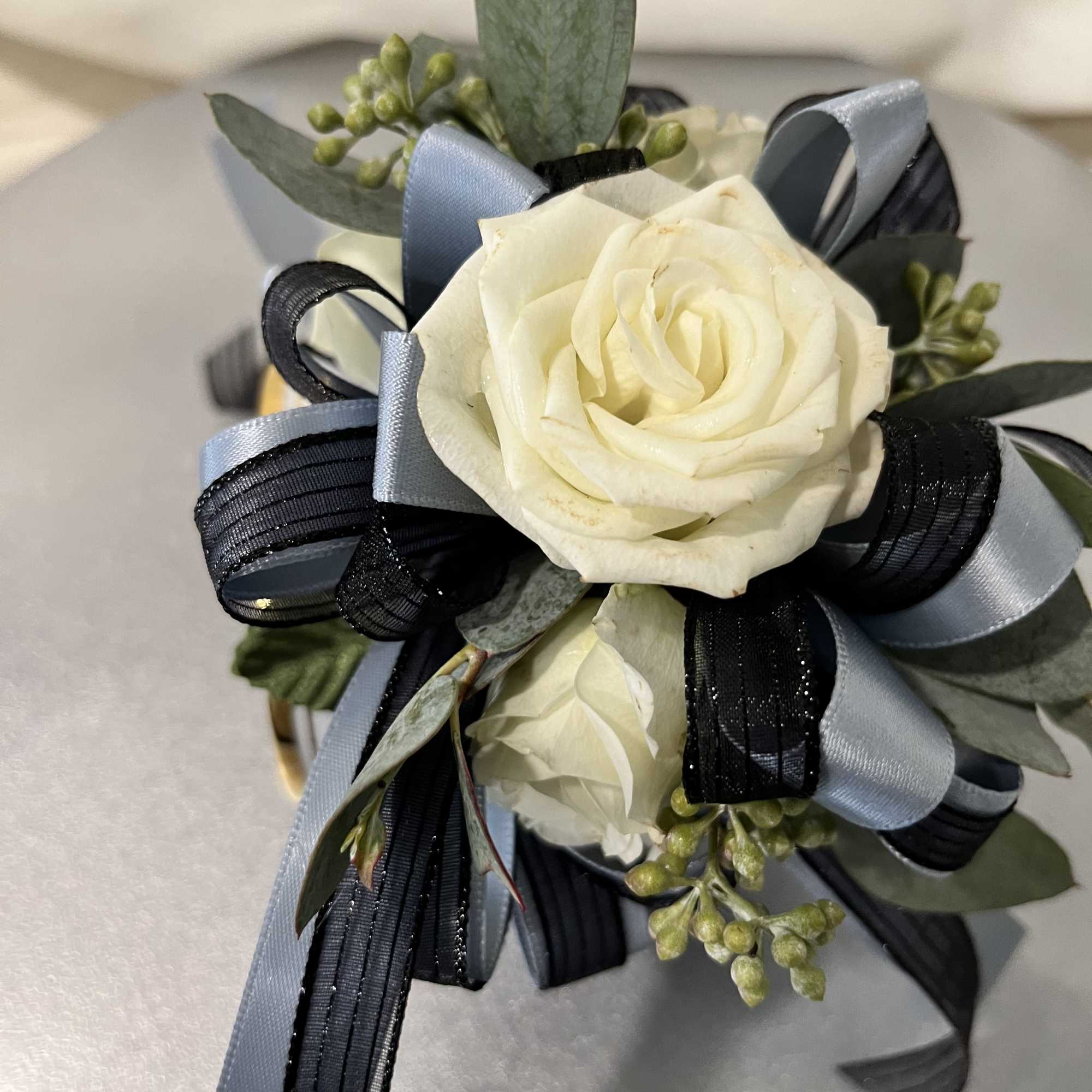 White rose corsage with blue and black ribbon accents