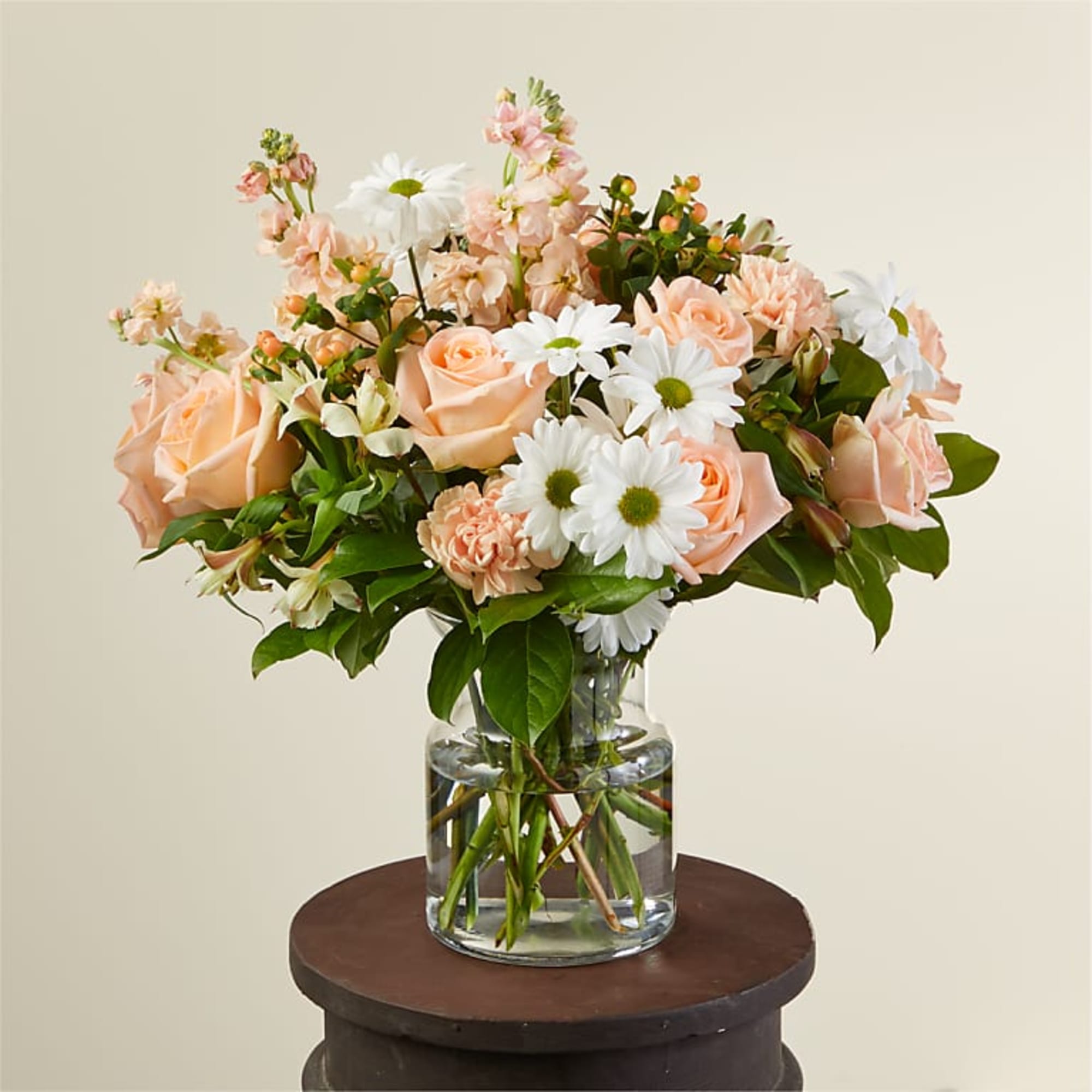 Peach roses and white daisies in a clear glass vase