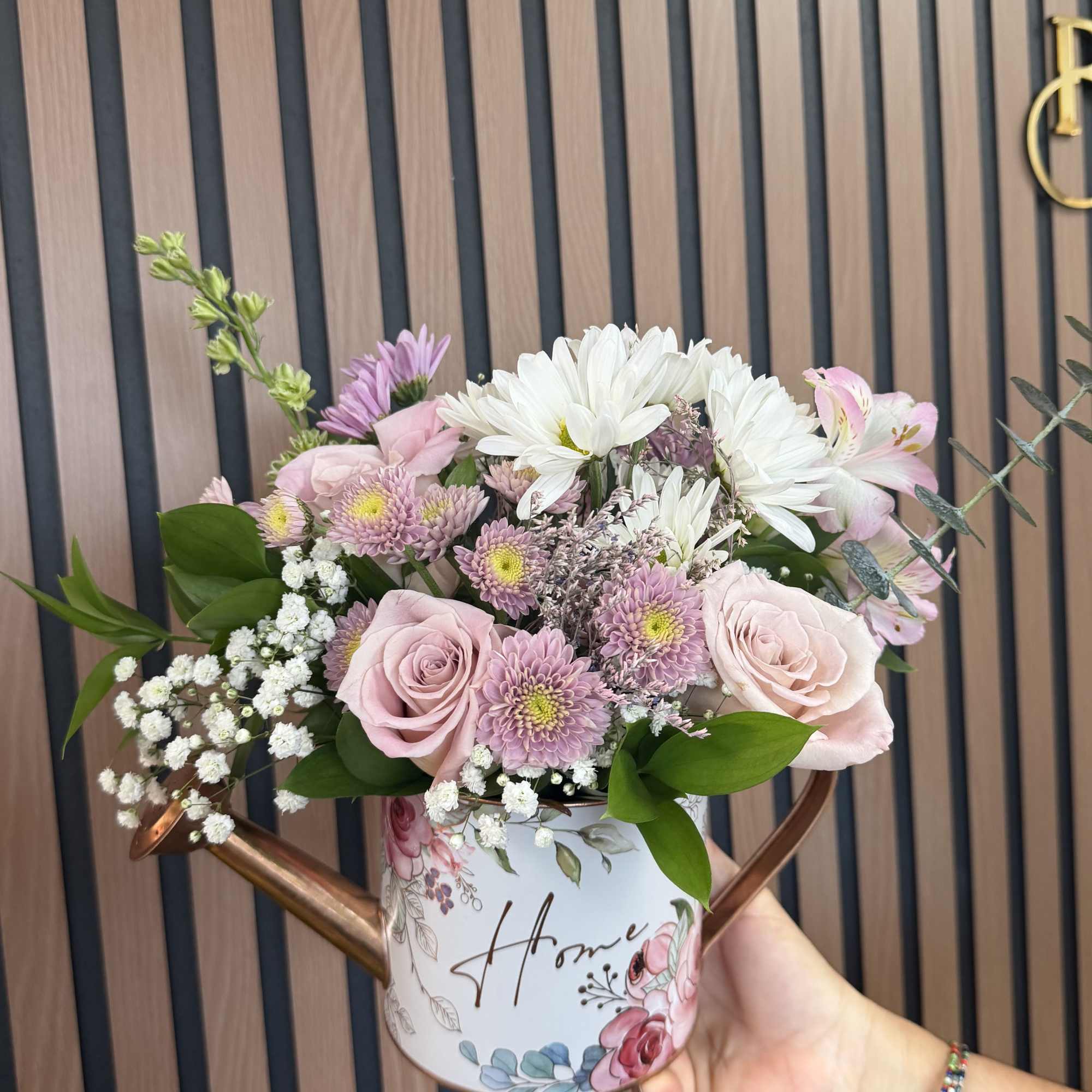 Pale pink roses and soft lavender chrysanthemums spill from a charming decorative