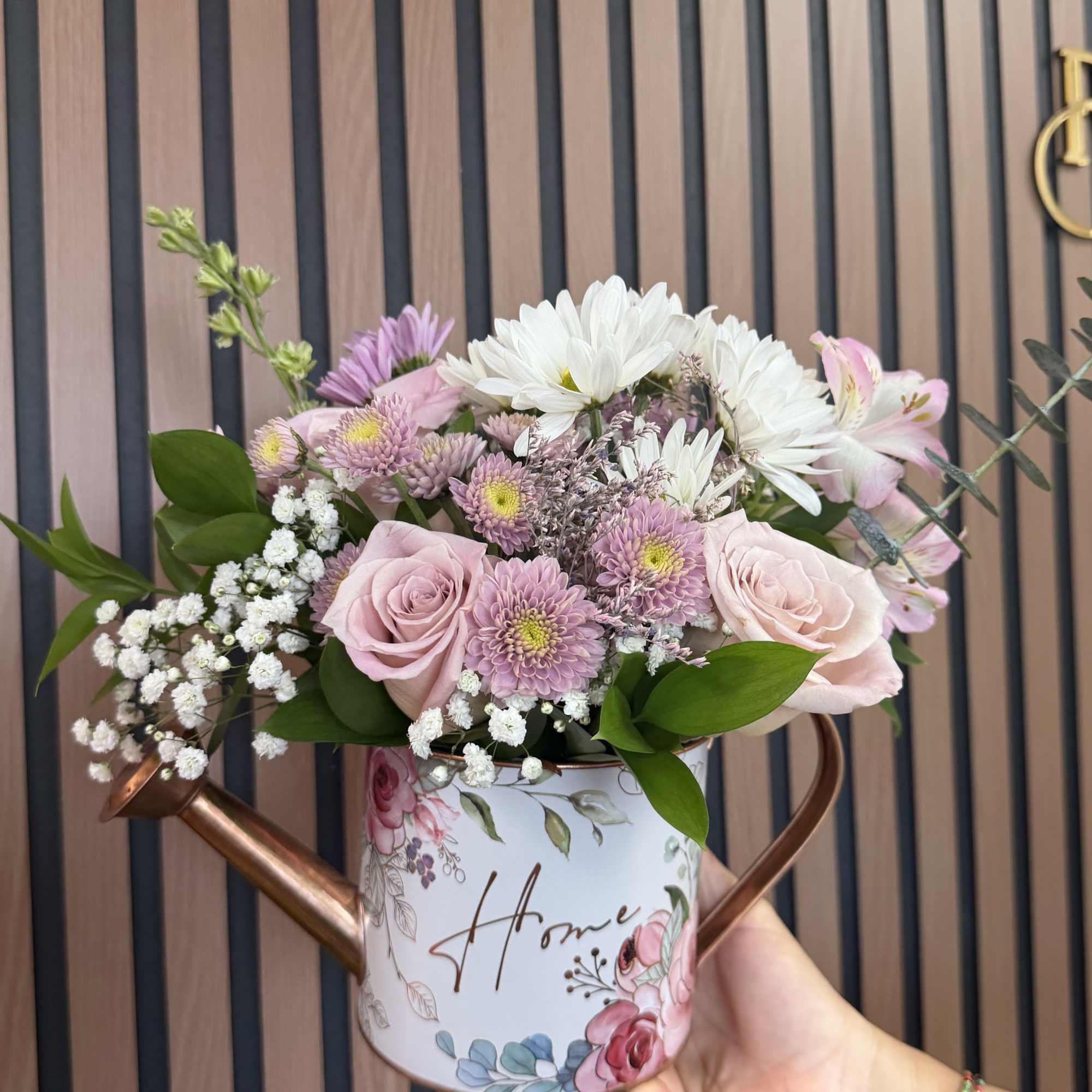 Pale pink roses and soft lavender chrysanthemums spill from a charming decorative
