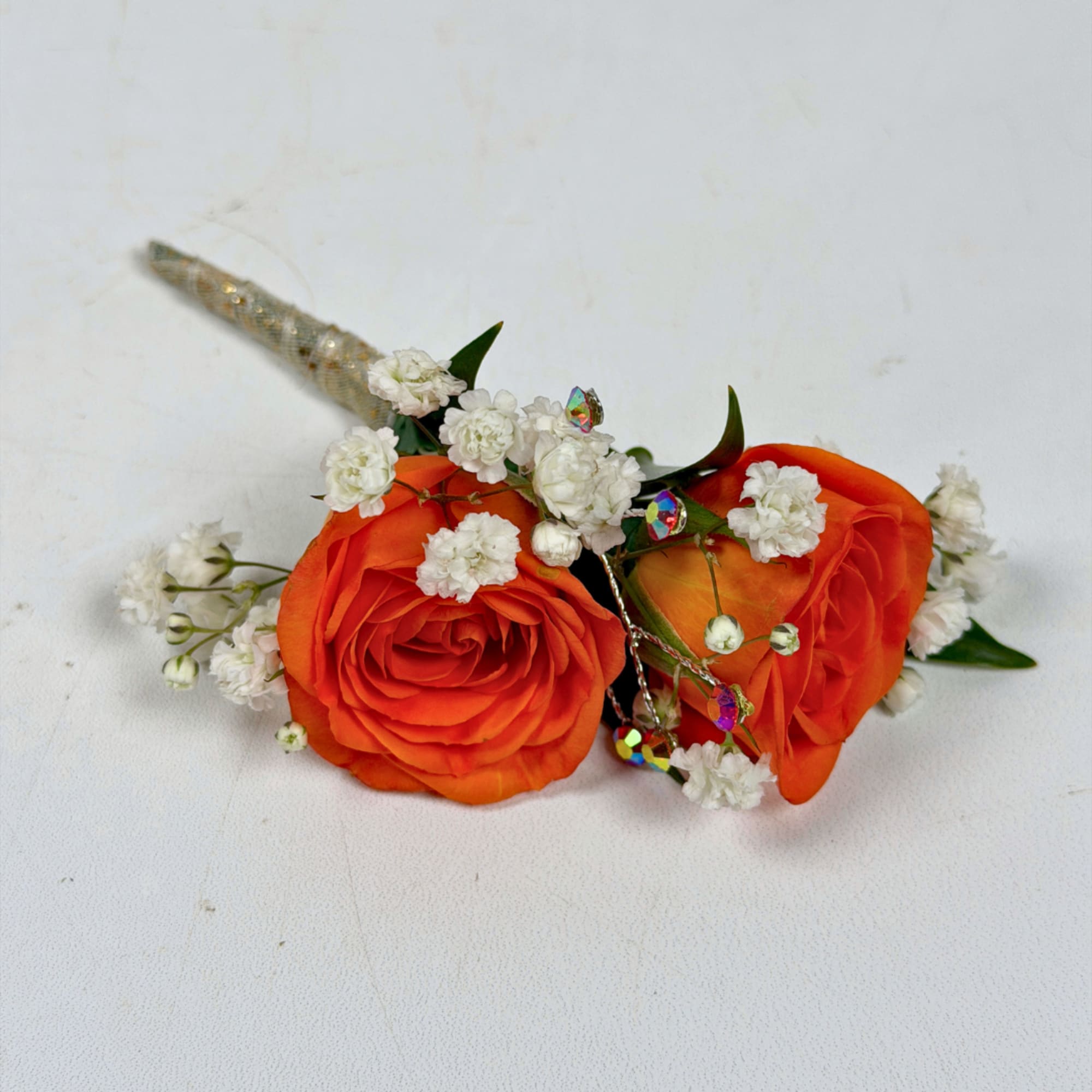 Two vivid orange rose blooms make this boutonniere a bright, celebratory accent