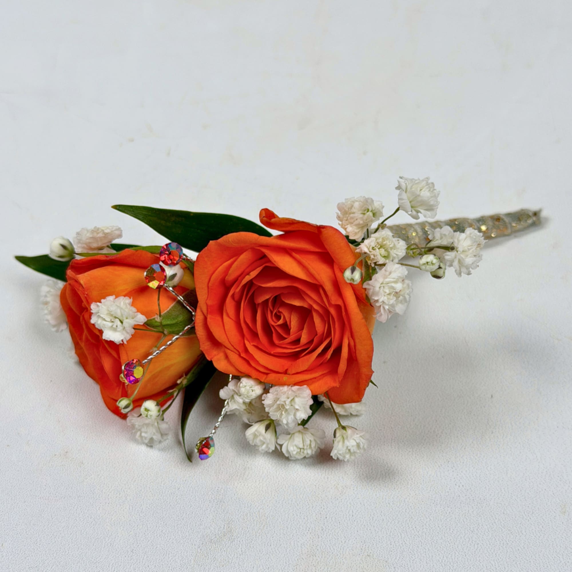 Two vivid orange rose blooms make this boutonniere a bright, celebratory accent