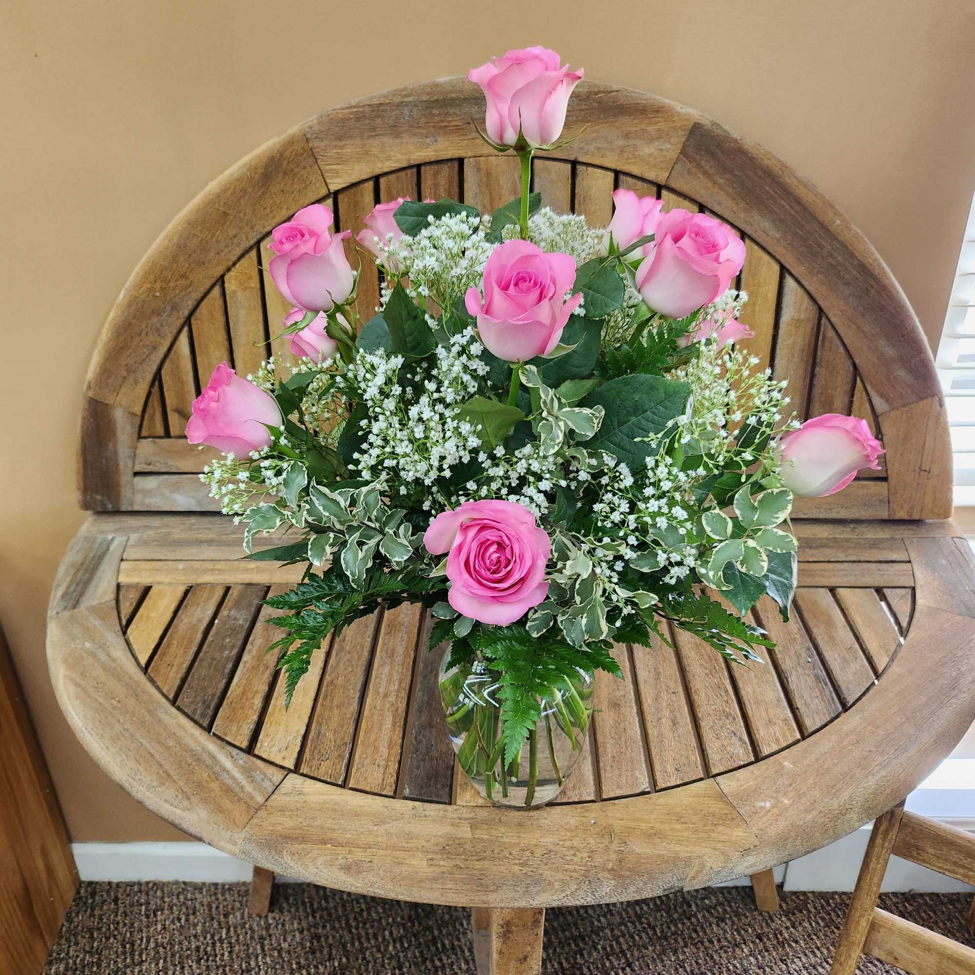 Pink roses arranged in a clear glass vase with white filler flowers