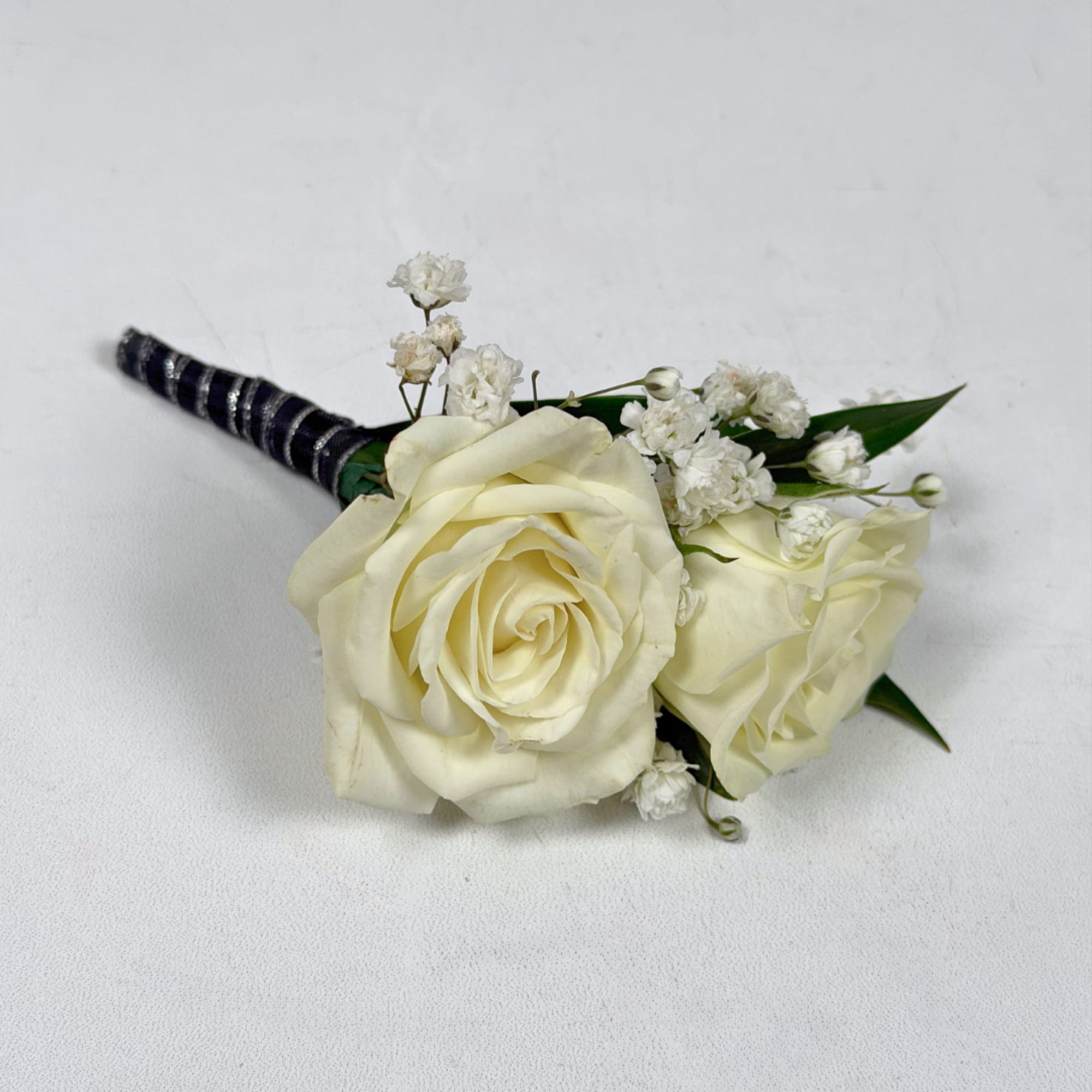 Two ivory-white roses create the refined focal point of Onyx Boutonniere, a