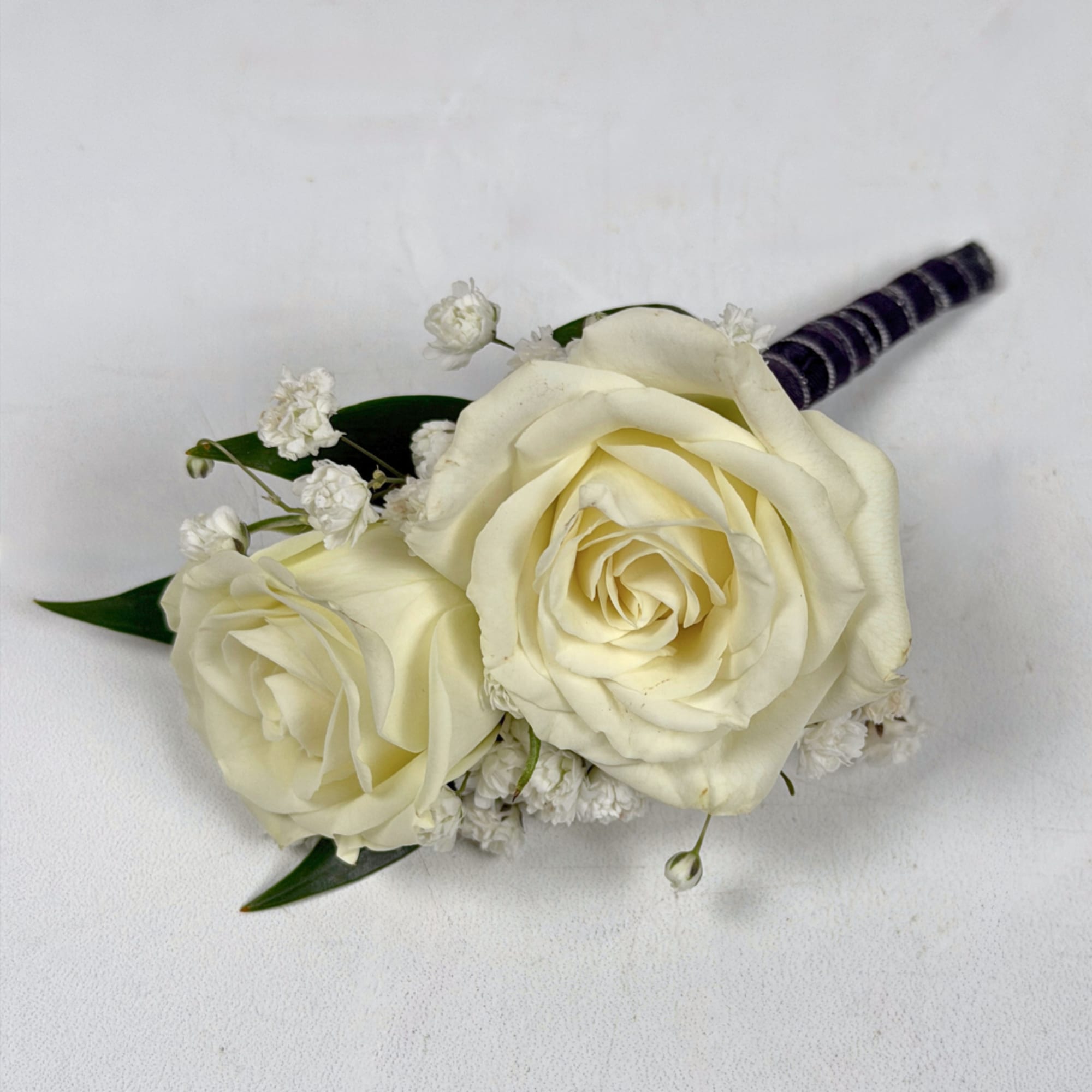 Two ivory-white roses create the refined focal point of Onyx Boutonniere, a