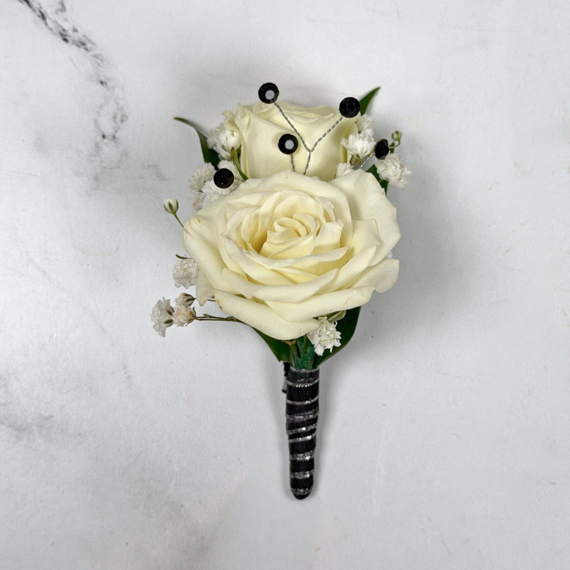 Two ivory-white roses create the refined focal point of Onyx Boutonniere, a