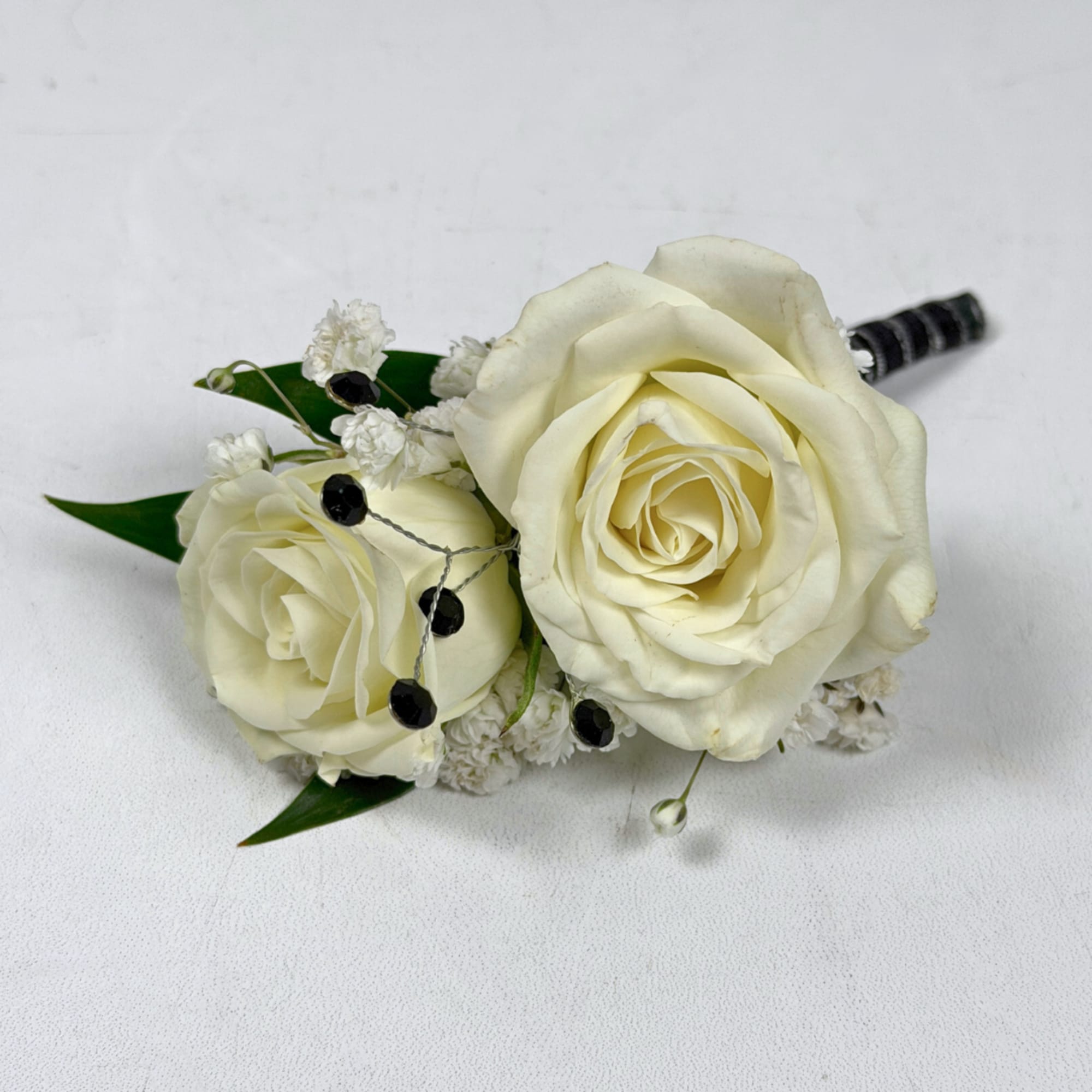Two ivory-white roses create the refined focal point of Onyx Boutonniere, a