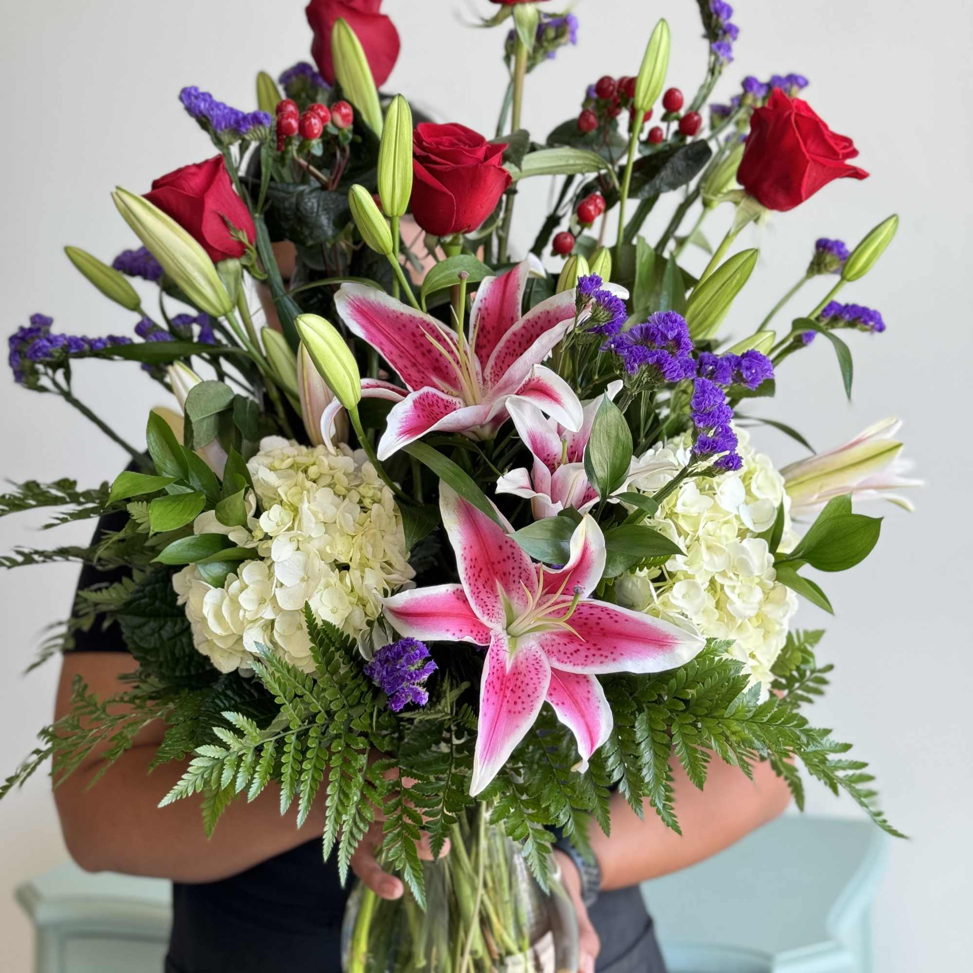 Bouquet of red roses, pink lilies, and white hydrangeas in a glass vase