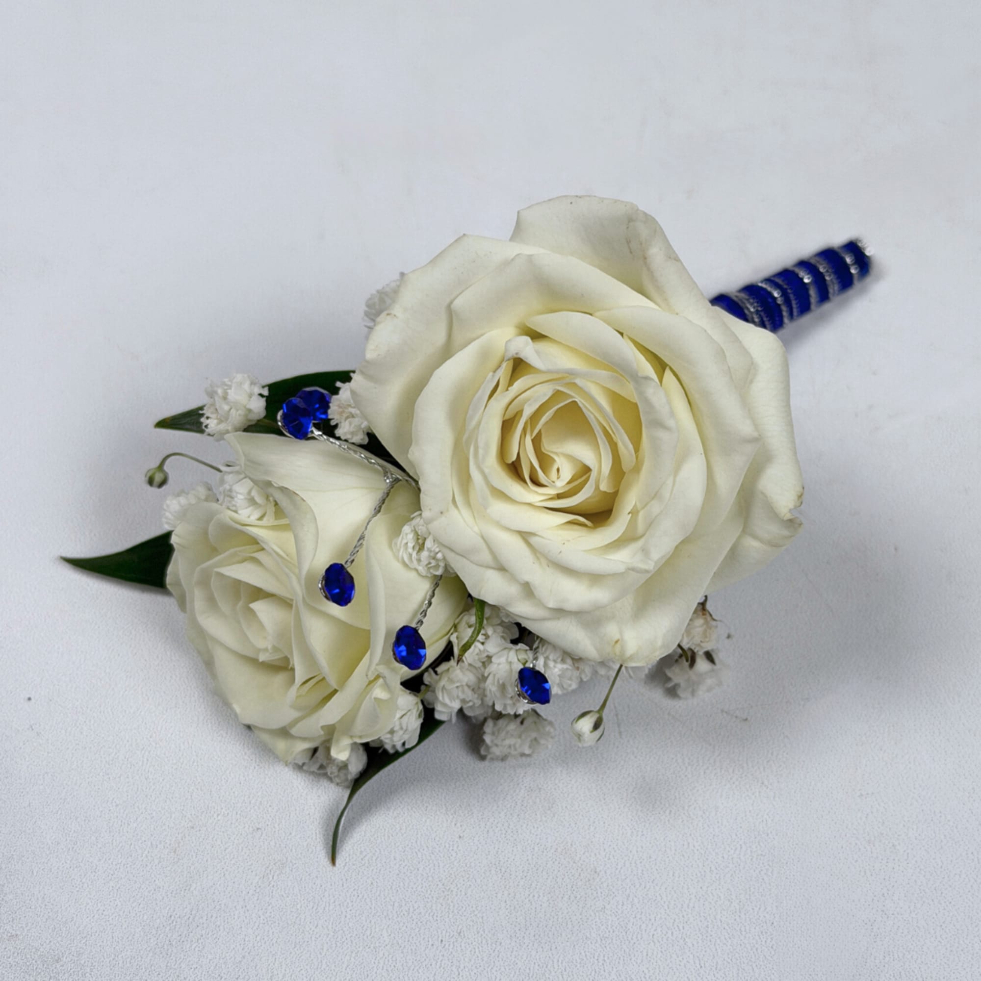 Two cream-white roses, clustered tightly with delicate white filler blooms and dark