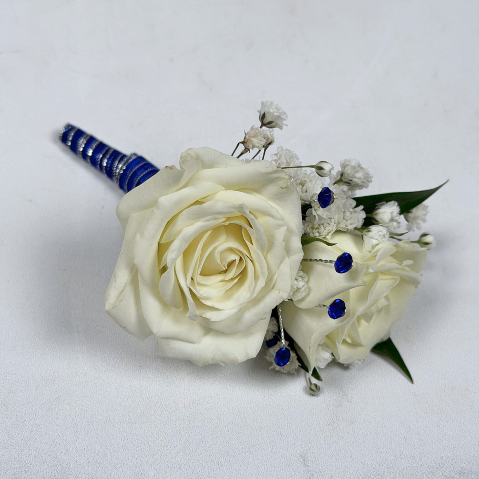 Two cream-white roses, clustered tightly with delicate white filler blooms and dark