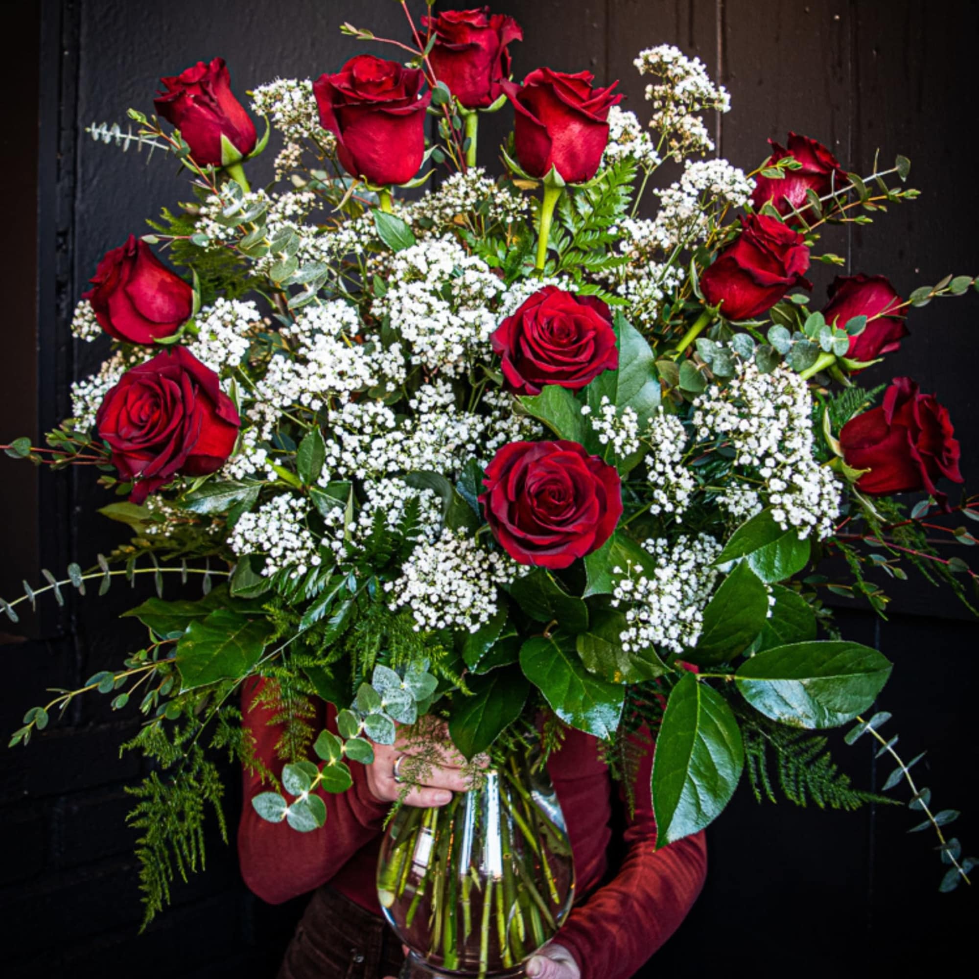 Bouquet of red roses and white filler flowers in a glass vase