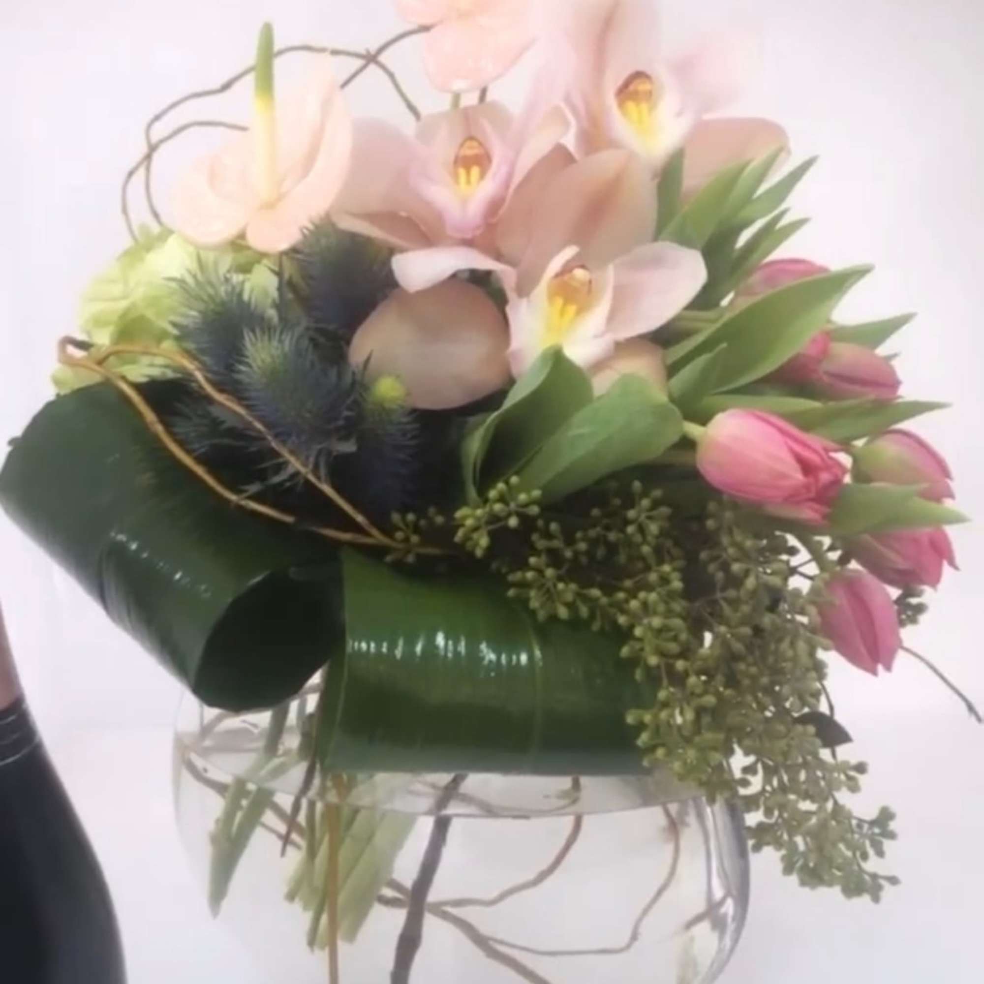 Pink anthuriums and tulips arranged in a clear glass vase