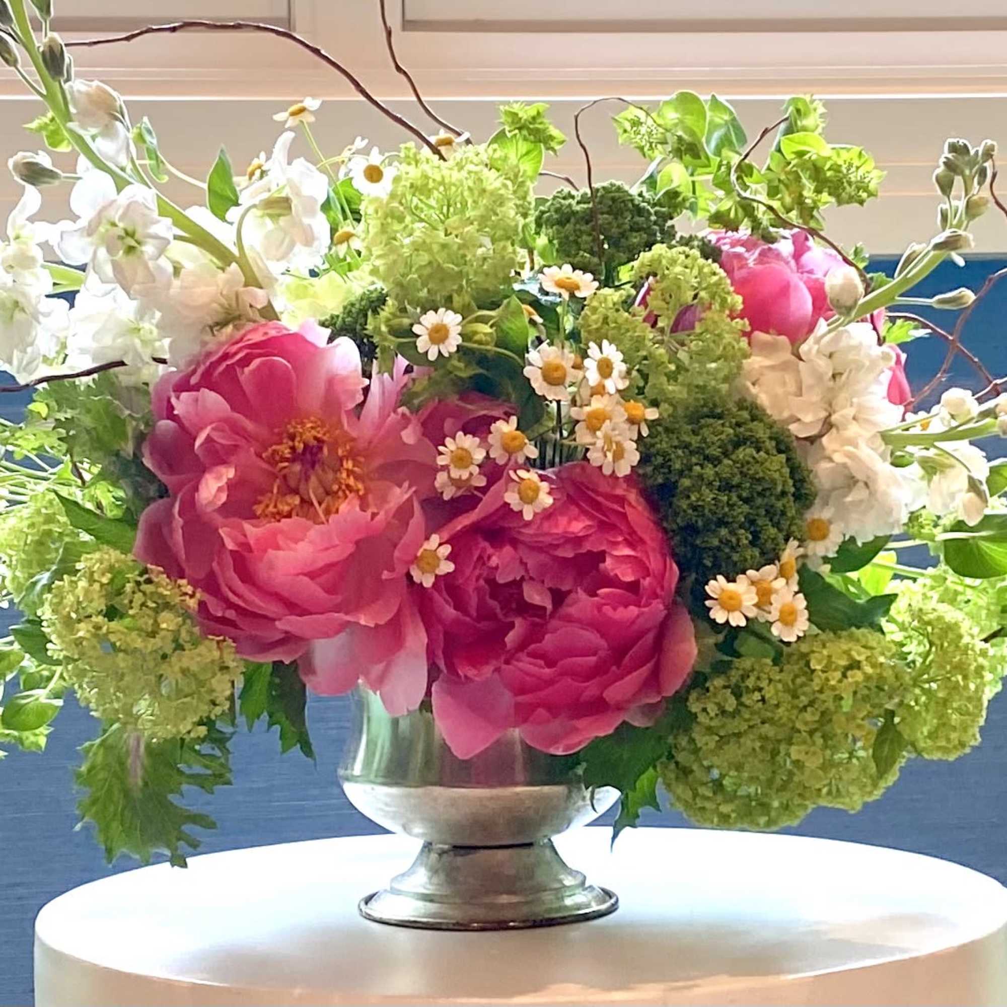 Pink and white floral arrangement in a silver vase