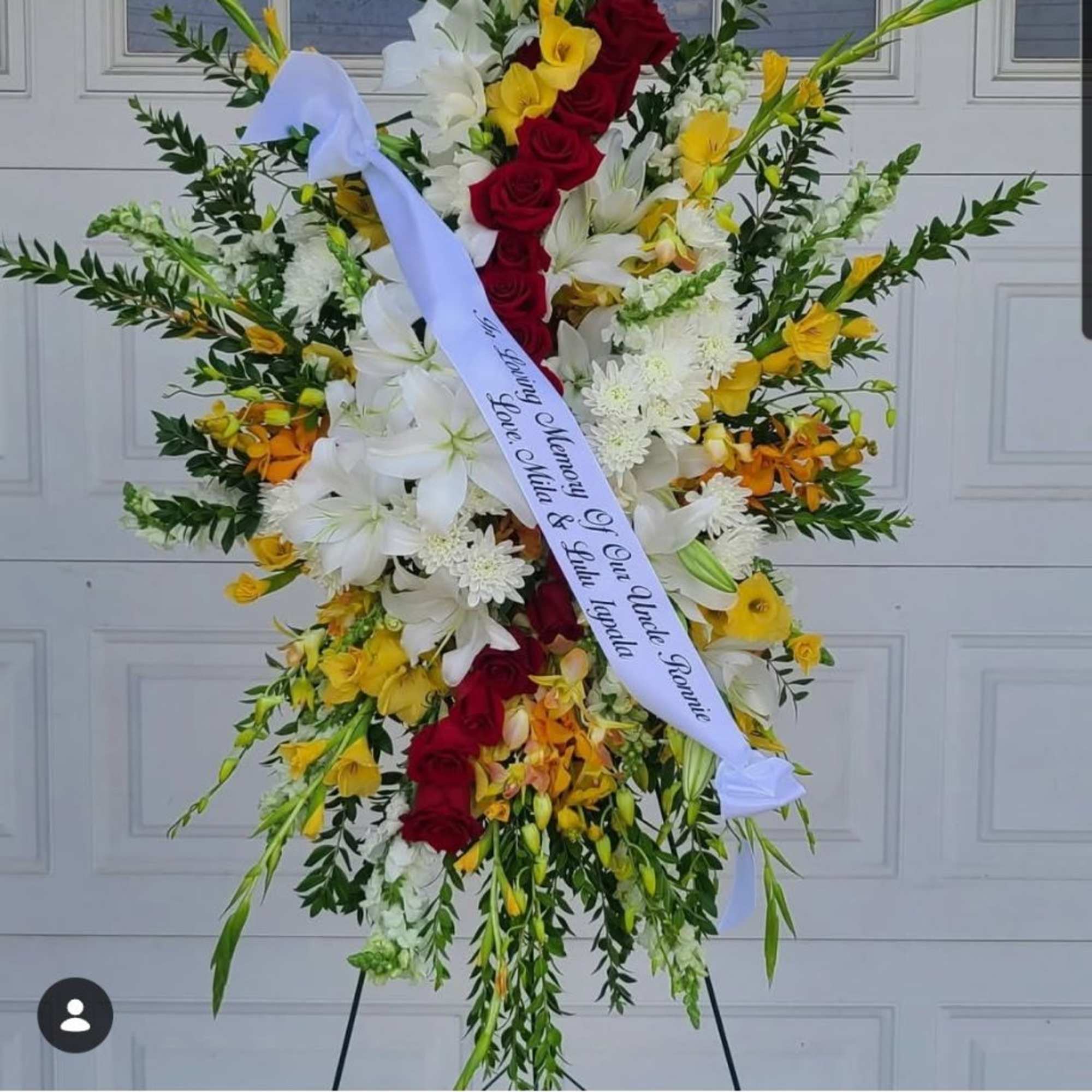 A tall, formal sympathy standing spray that combines deep red roses with