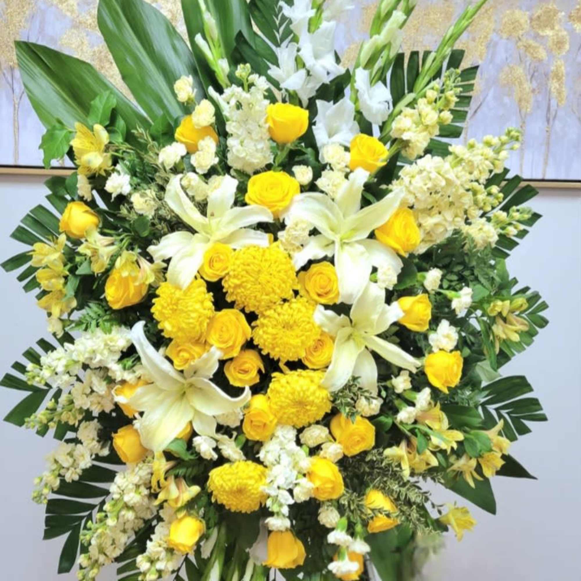A bright yellow-and-white standing spray that brings a hopeful, respectful presence to