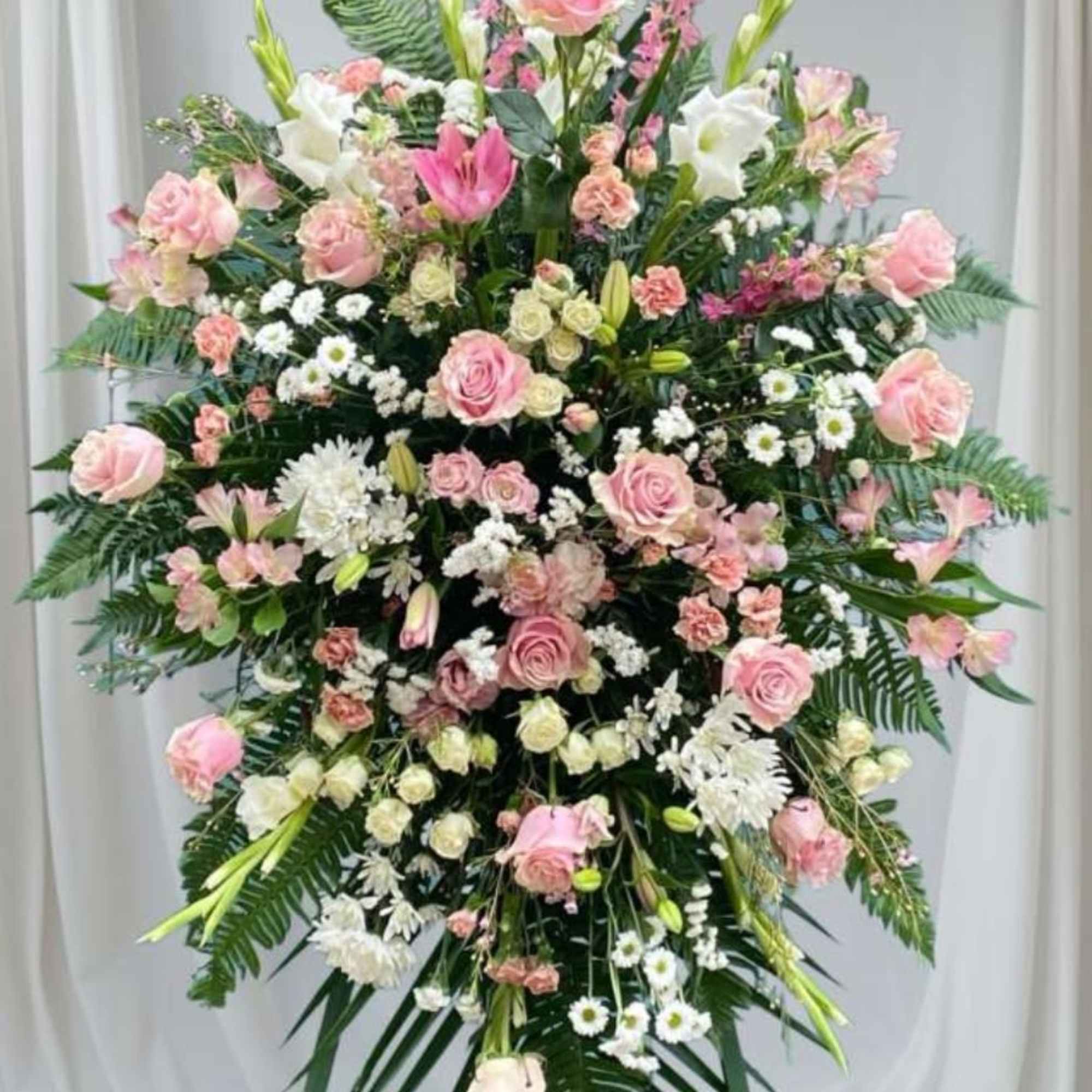 Soft pink roses and pale lilies form the heart of this sympathy