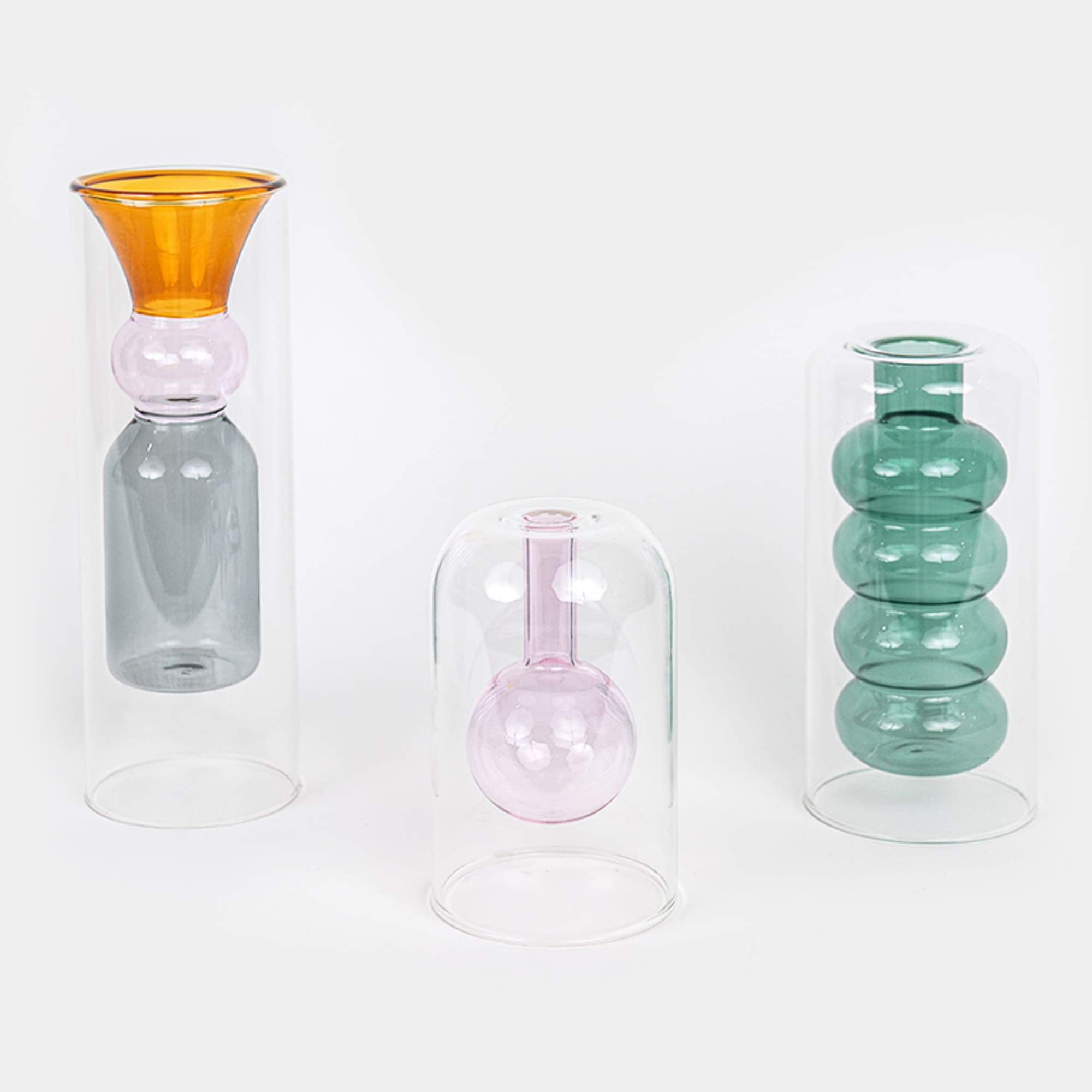Three colorful glass vases under clear cloches