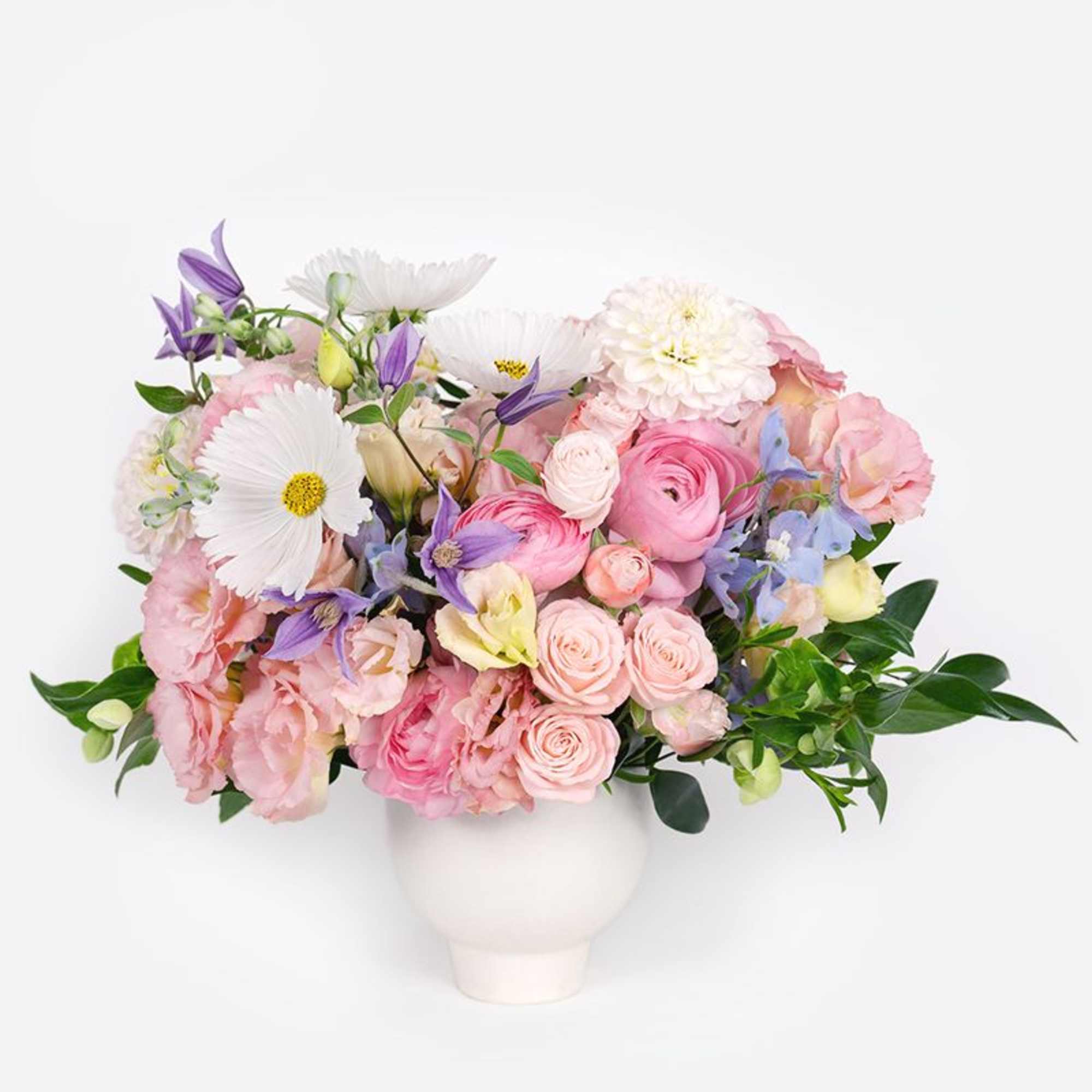 Soft and romantic, this pastel arrangement features roses, ranunculus, lisianthus, delphiniums, and