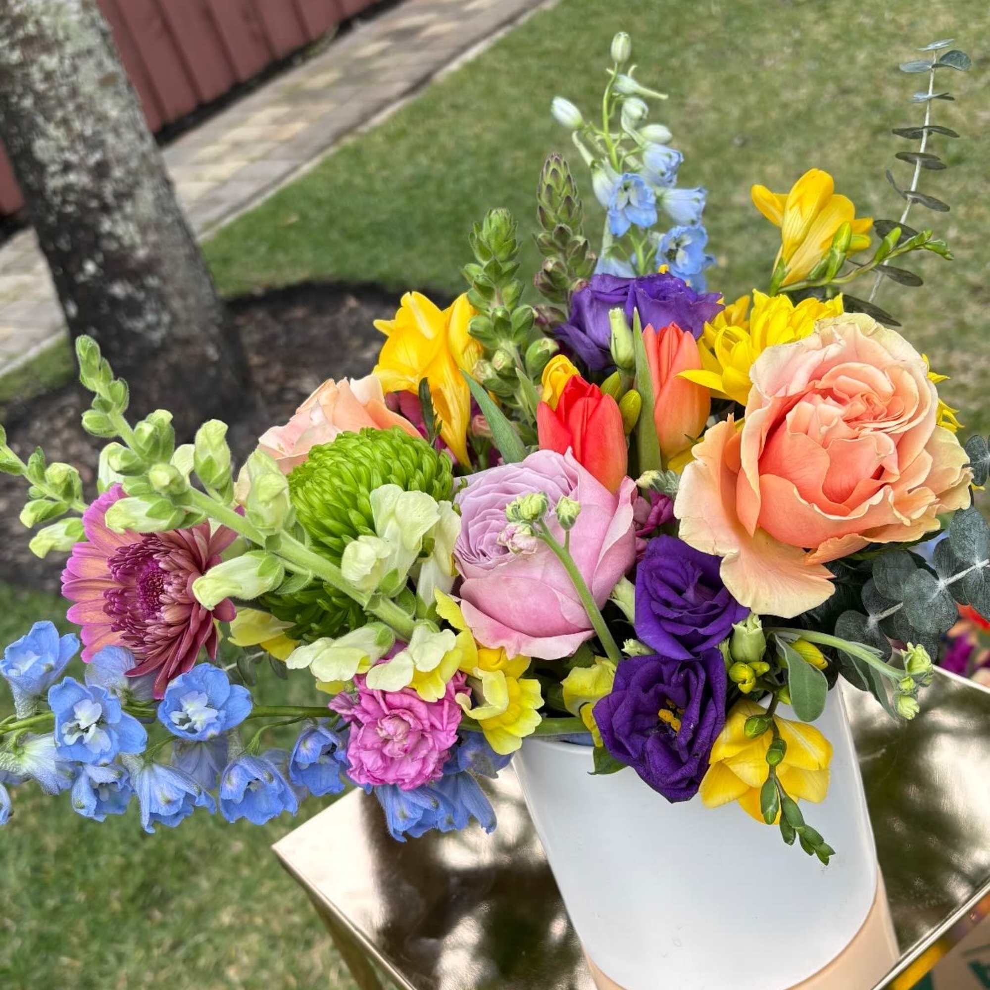 Colorful mixed bouquet in a white vase on a gold stand.