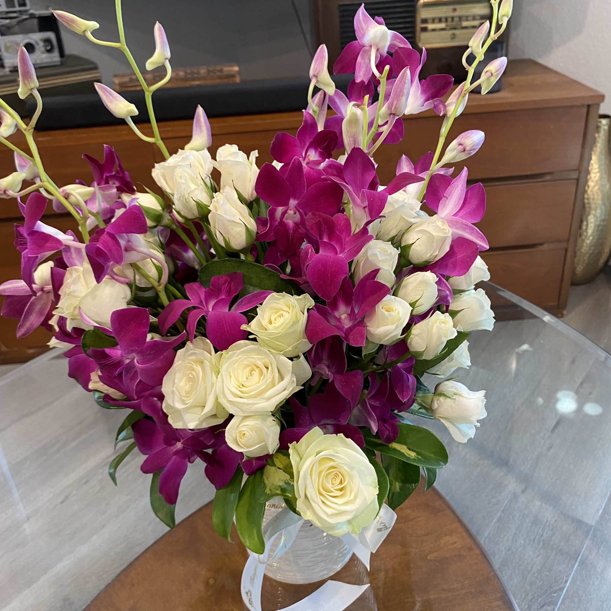 Bouquet of white roses and magenta orchids in a clear vase