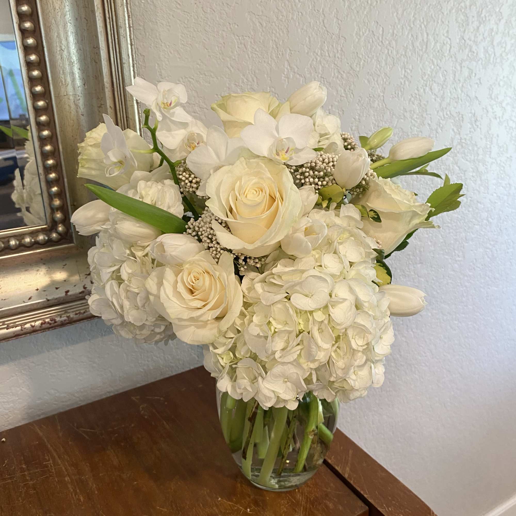 White roses and hydrangeas arranged in a clear glass vase
