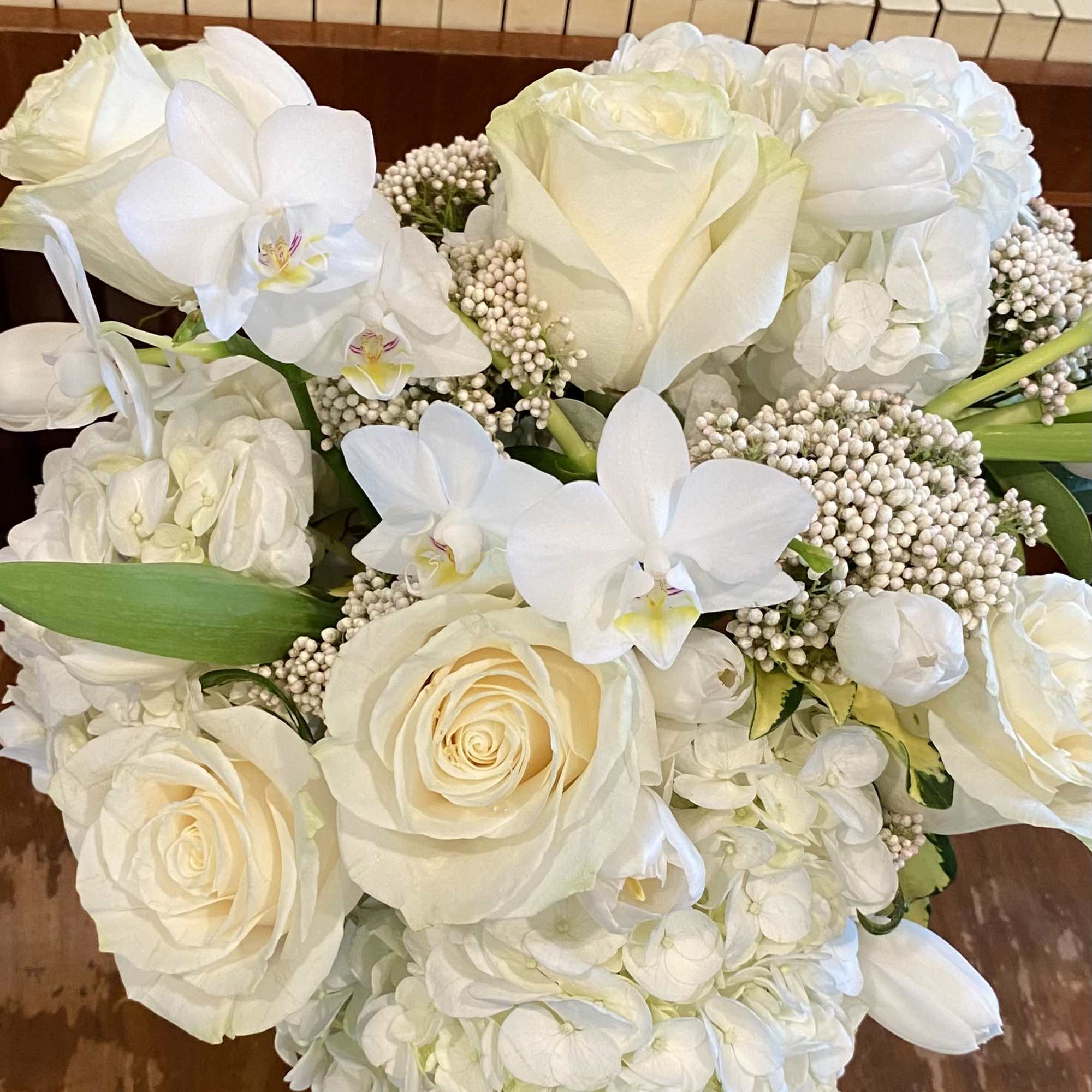 White roses and orchids arranged with hydrangea clusters