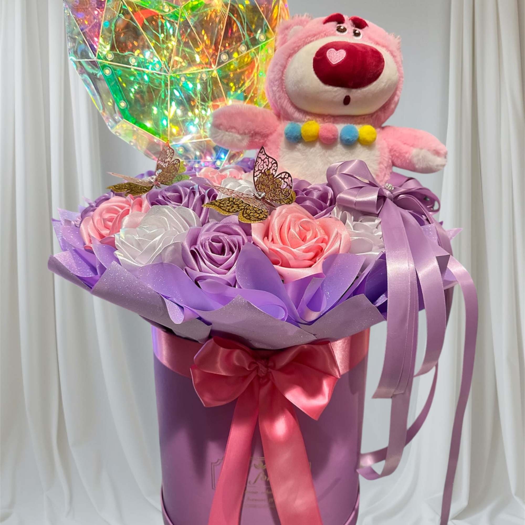 Pink teddy bear in a purple gift box with satin roses and a holographic heart