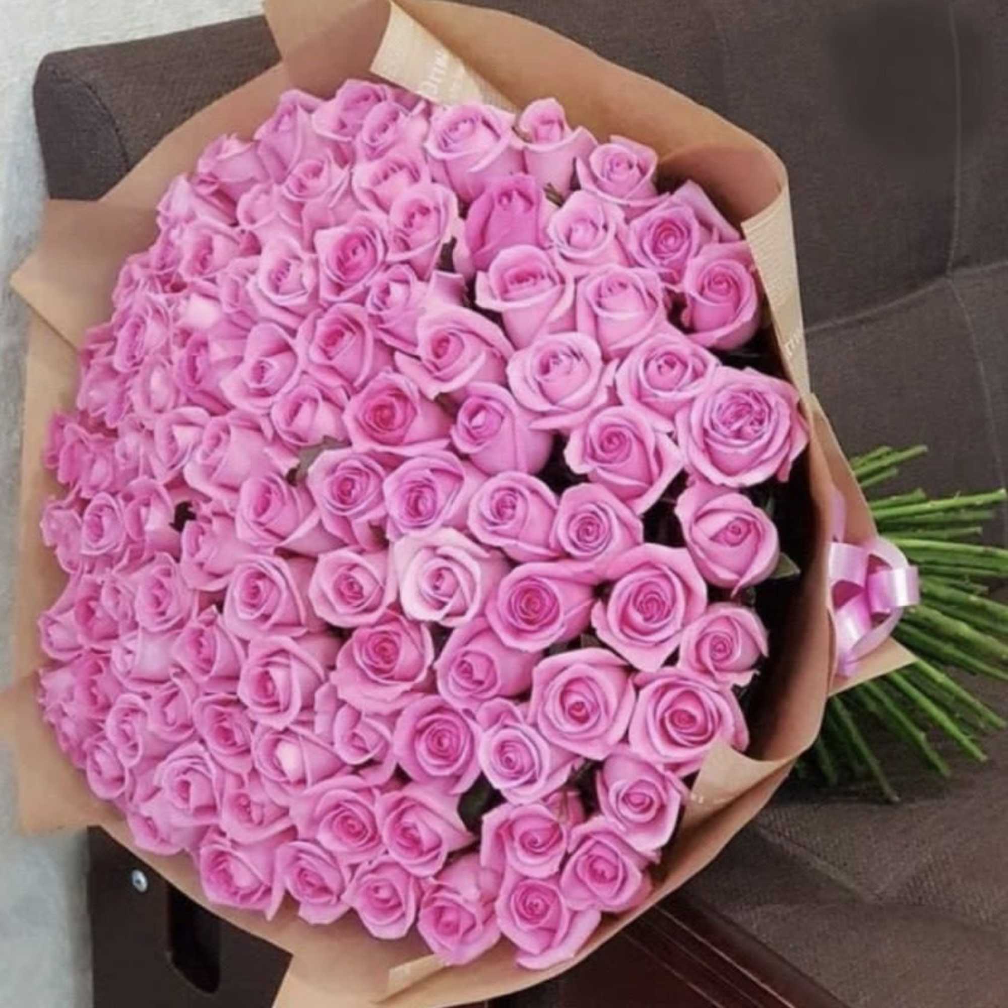 Large bouquet of pink roses wrapped in brown paper