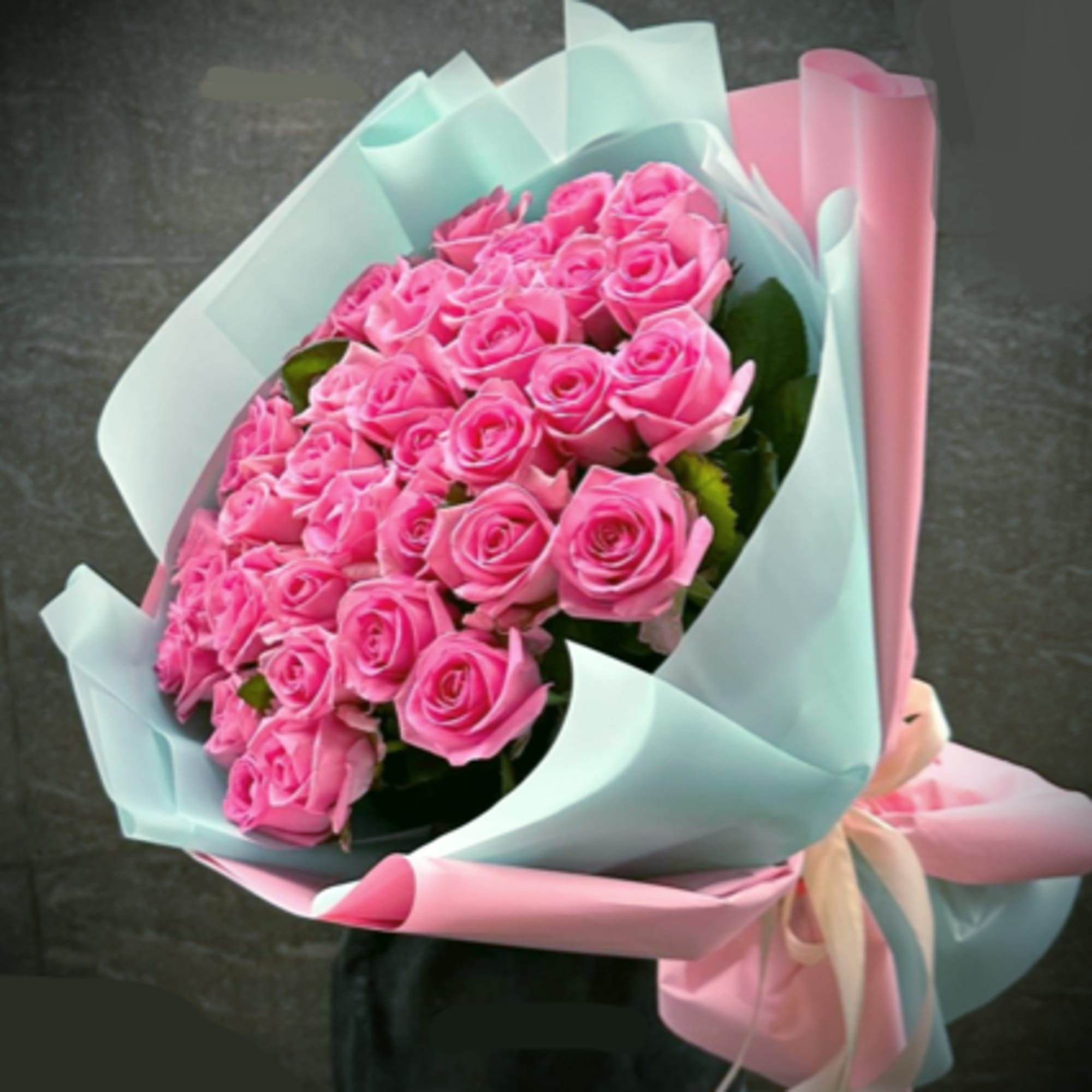 Bouquet of pink roses wrapped in pastel blue and pink paper