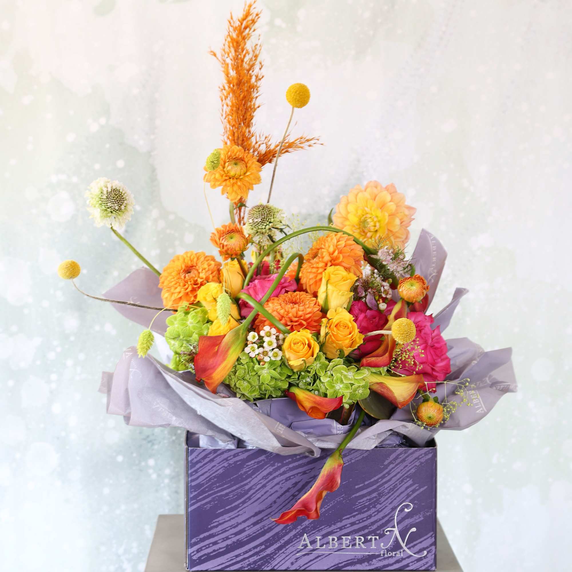 A cheerful orange, fuchsia, yellow green color palette vase arrangement create with