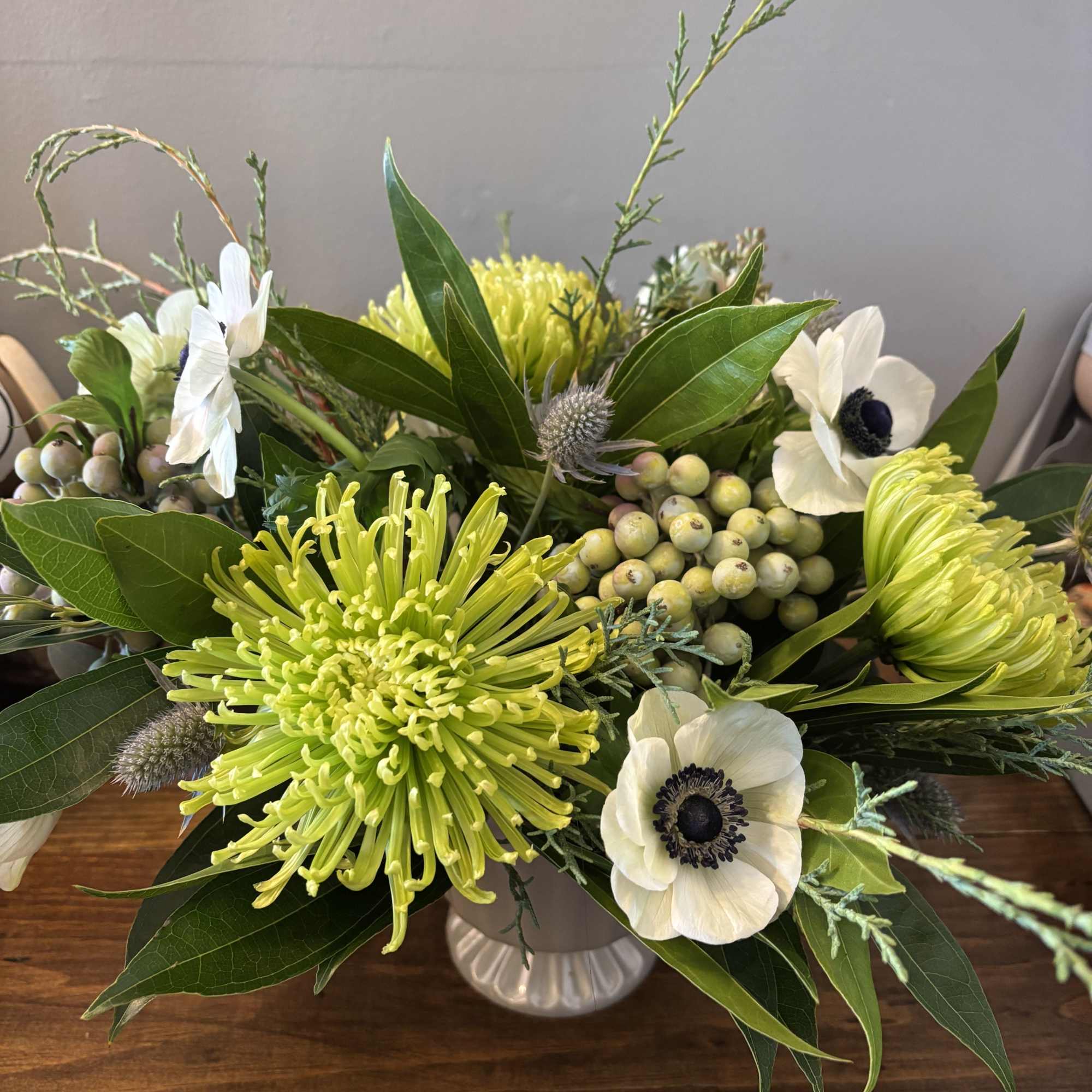 White anemones and lime-green chrysanthemums in a white vase